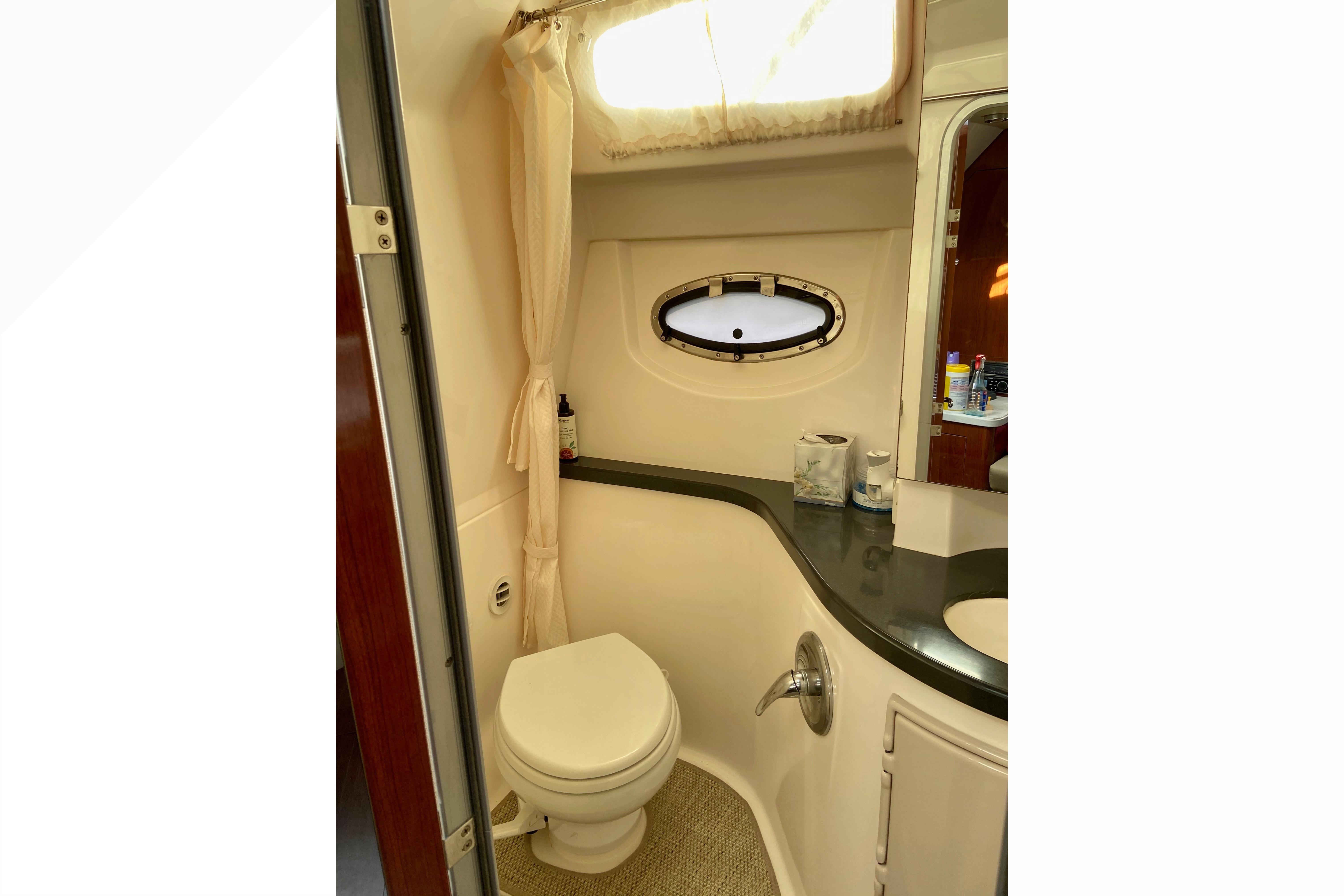 Bathroom interior of 2012 Regal 35 Express Cruiser with toilet, sink, and porthole window.