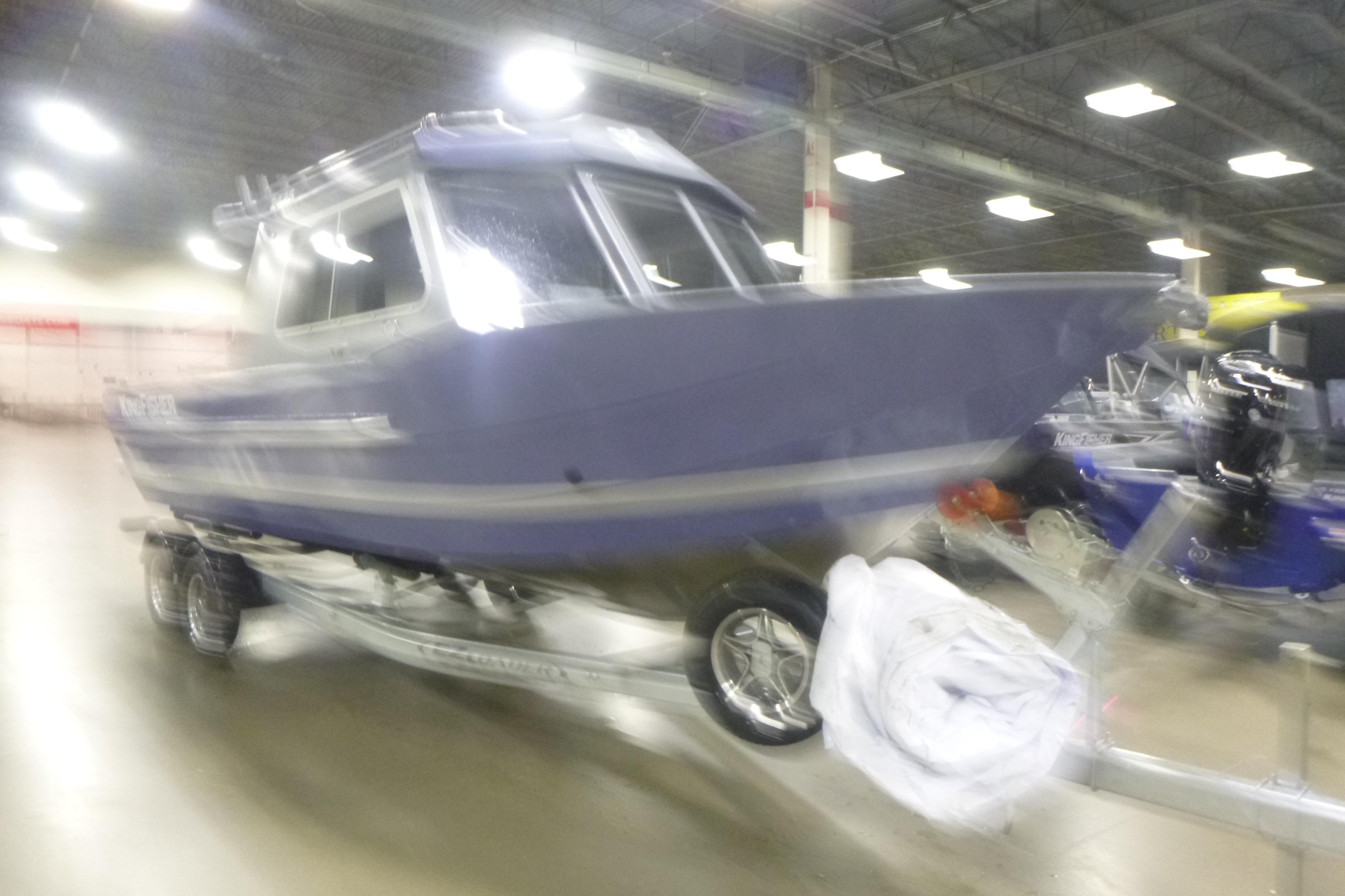 Blurry image of a 2026 KingFisher 2425 Escape HT boat on display indoors.