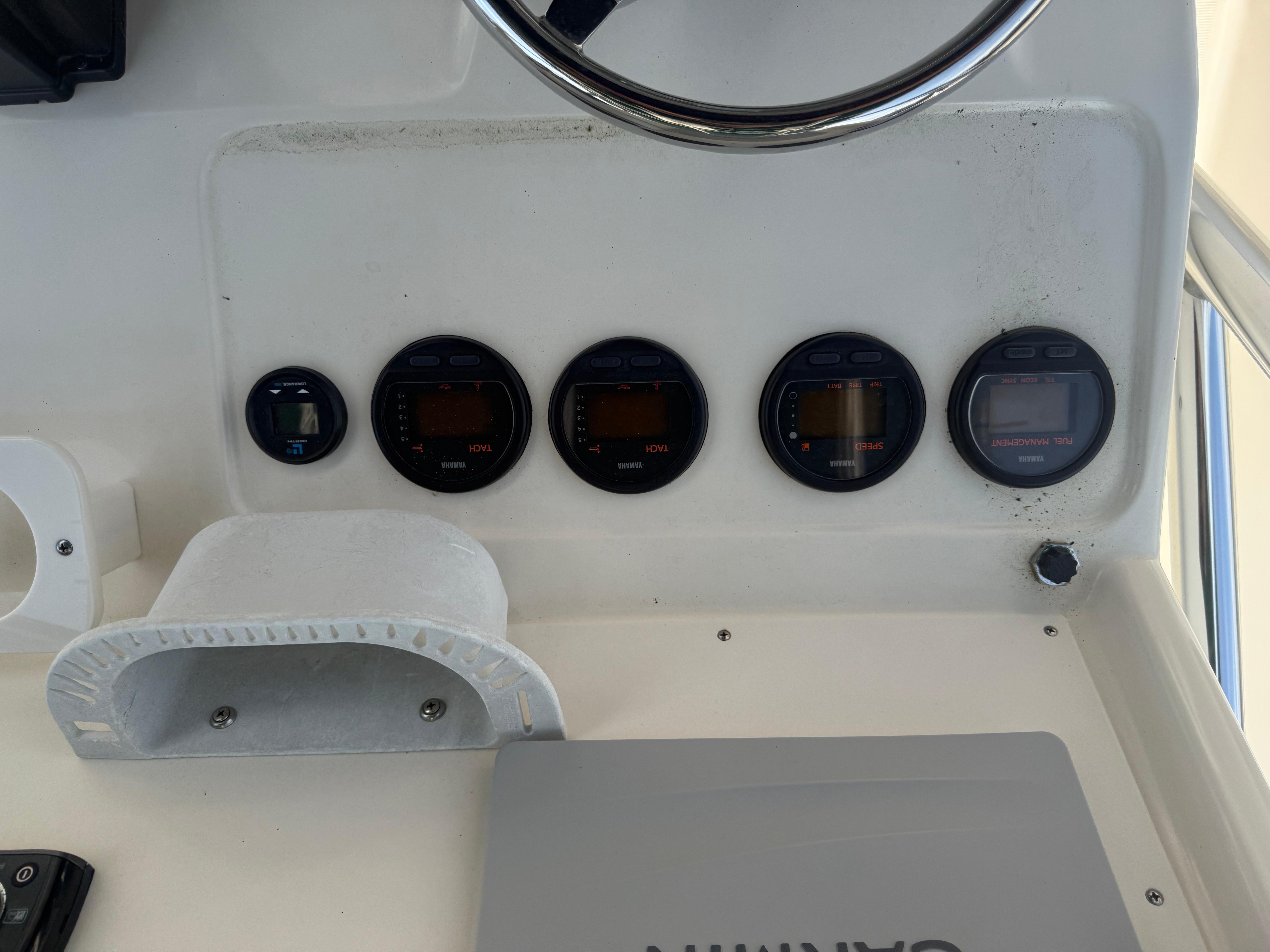 Dashboard of a 2002 Pursuit 2470 CC boat with gauges and steering wheel.
