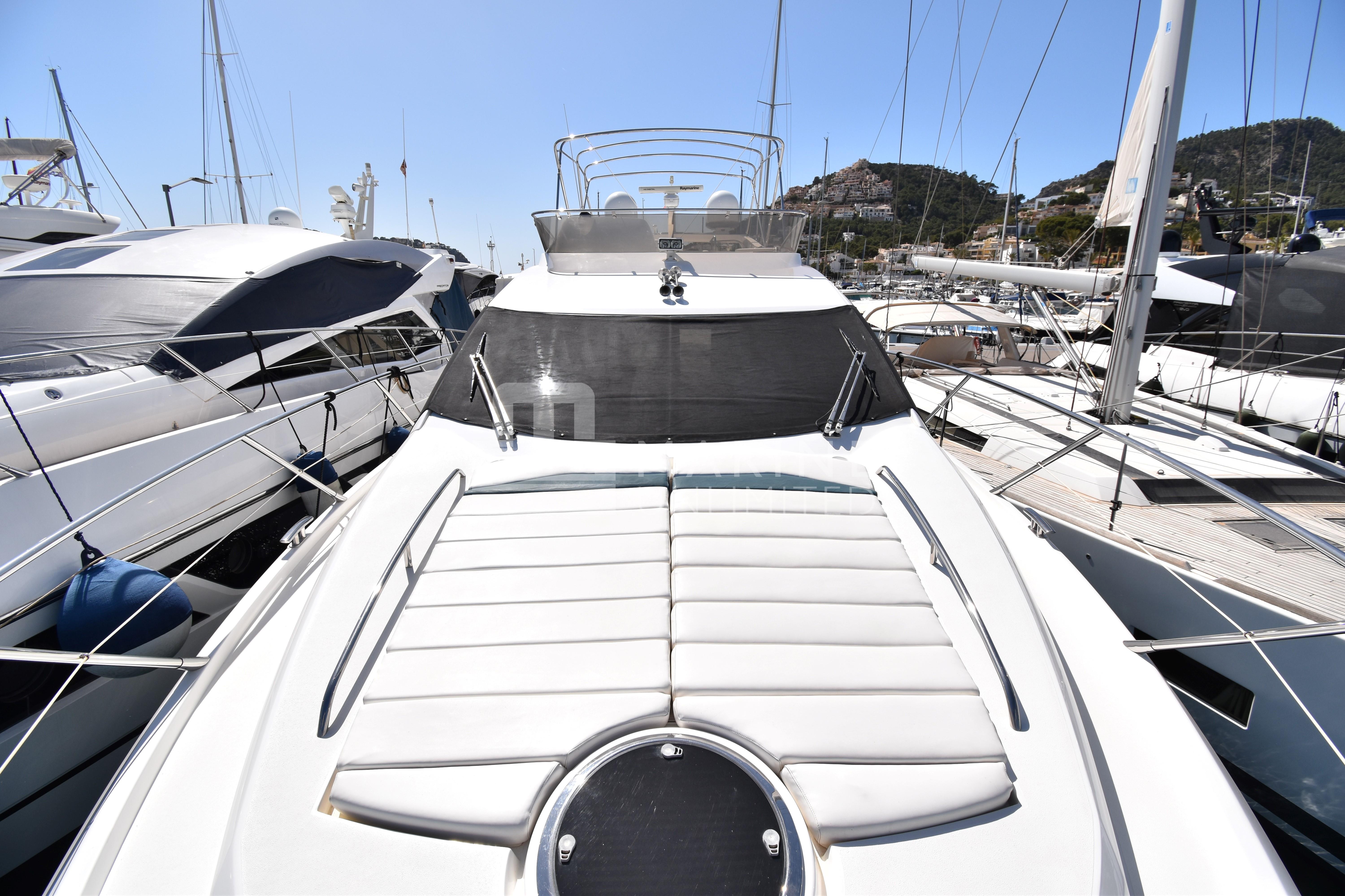 Sunseeker Manhattan 52 yacht, 2010 model, docked in a marina under clear skies.