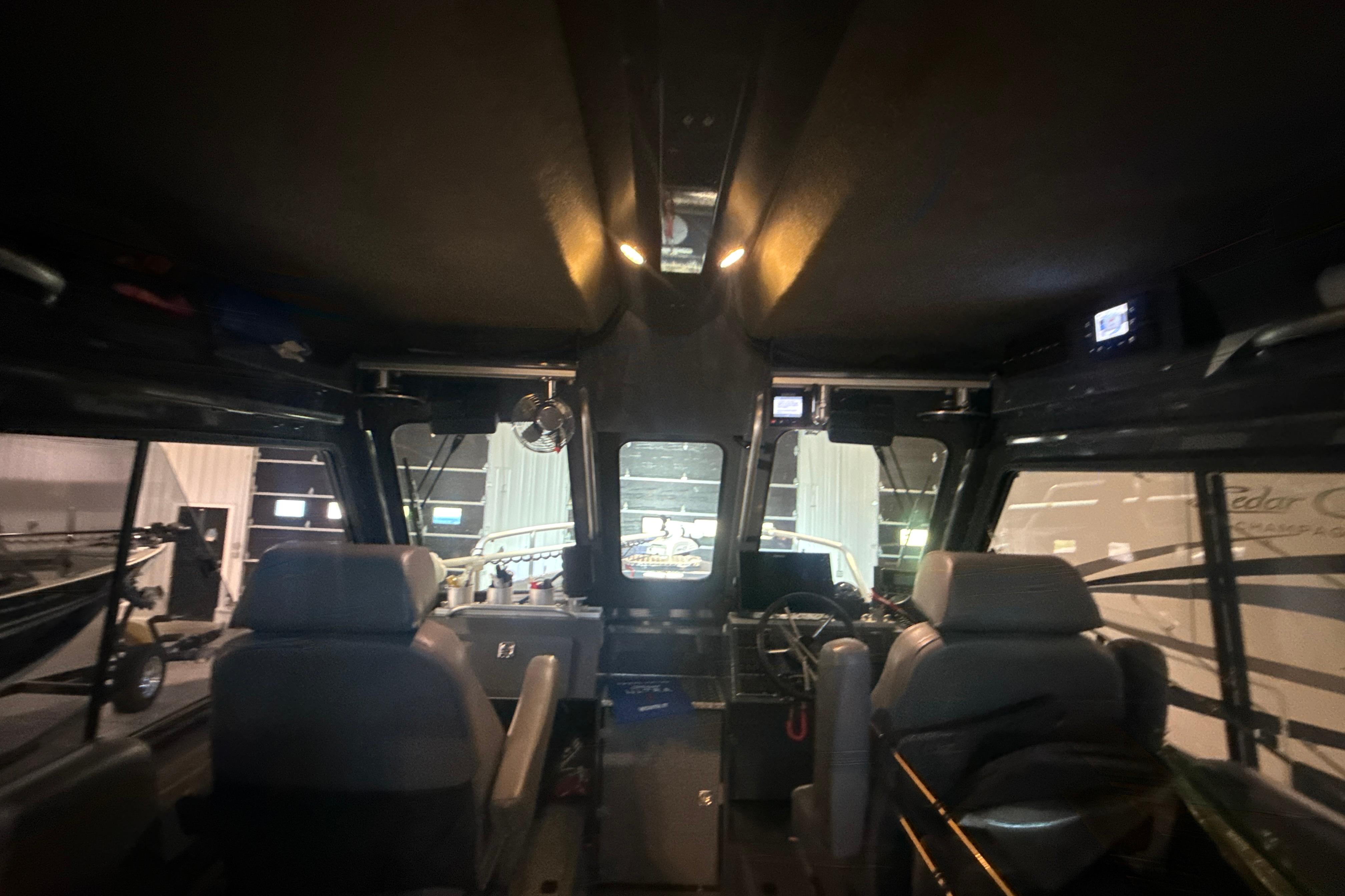 Interior view of 2022 Hewescraft 270 Alaskan Hardtop boat, showcasing seating and dashboard.
