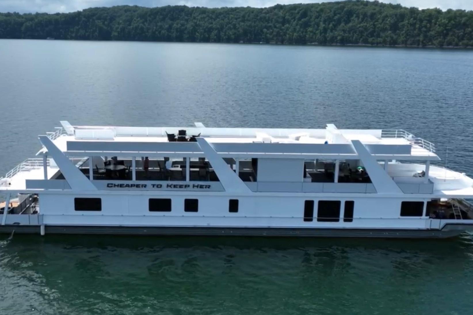 2022 Trifecta HOUSEBOAT on a lake, featuring spacious decks and modern design.