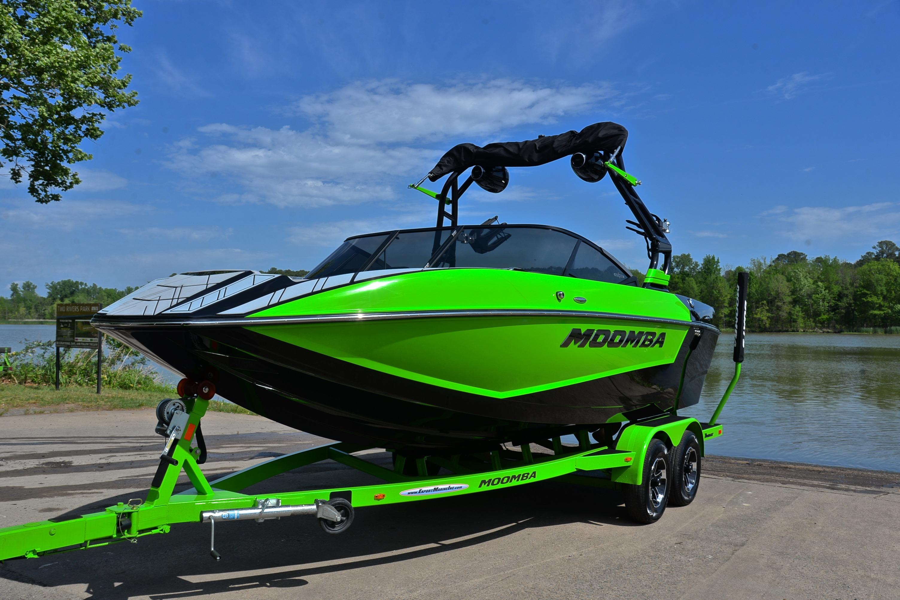 2024 Moomba Mondo boat in vibrant green on trailer by a lakeside.