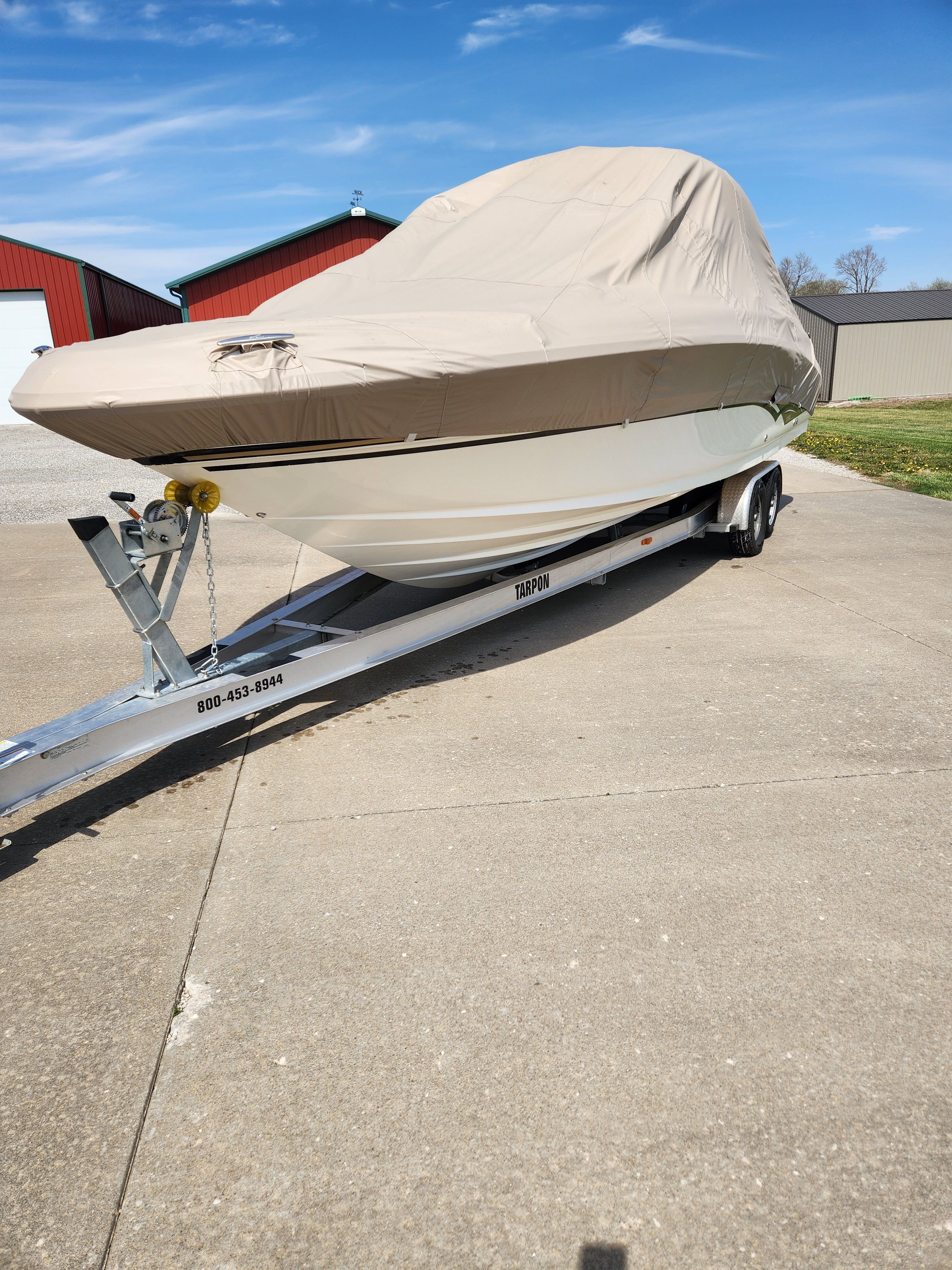 A covered boat on a trailer on a concrete surface.