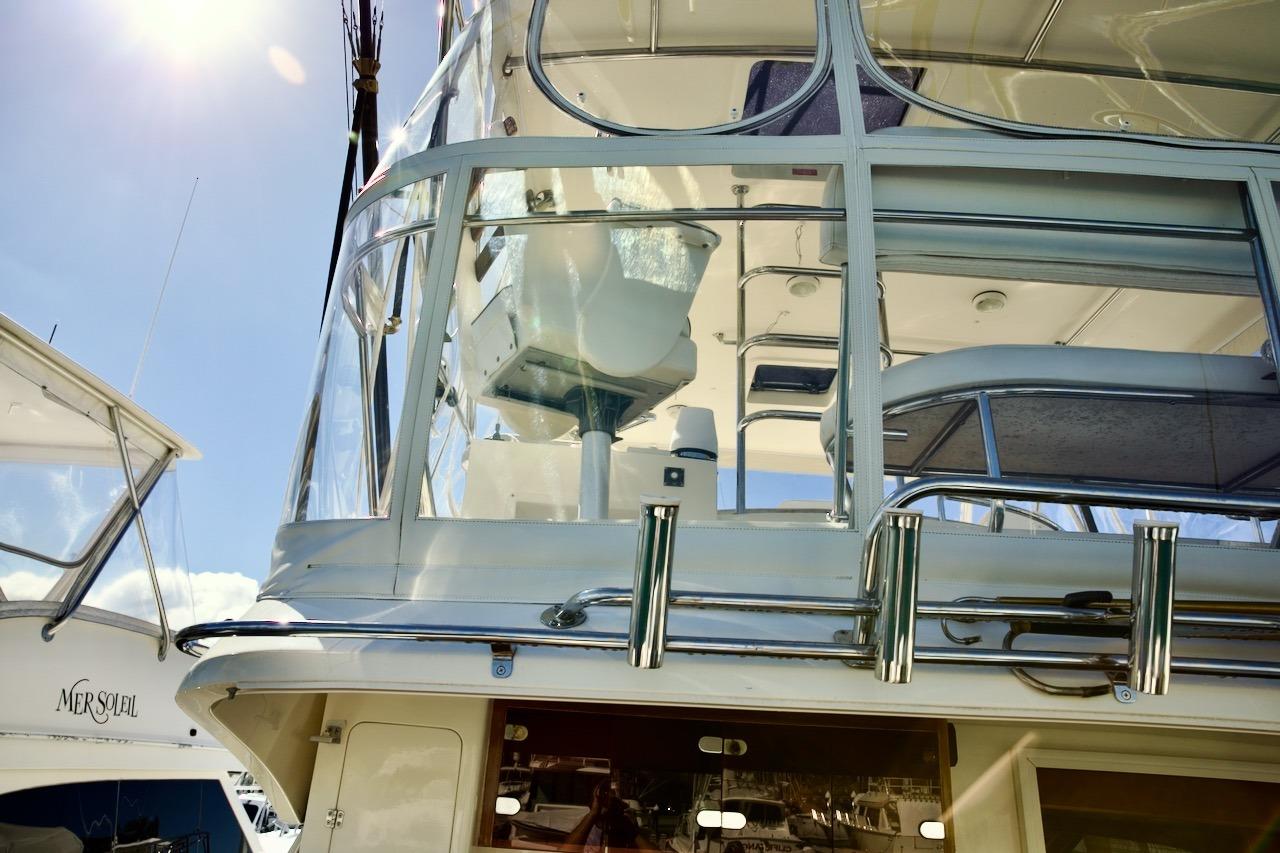 2002 Mikelson 50 Sportfisher yacht with upper deck and clear enclosure under sunny sky.