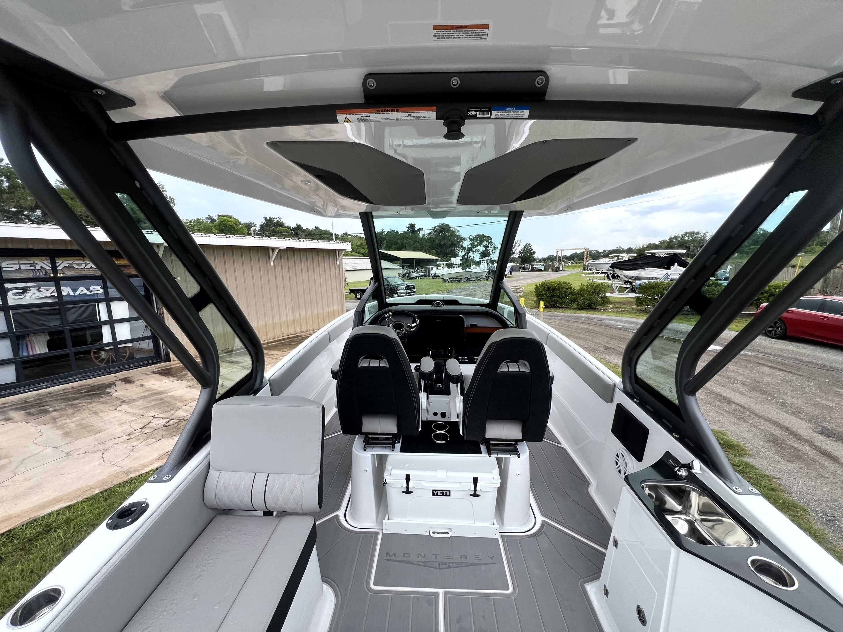 Interior view of a modern boat with two seats, a helm, and a small kitchenette.