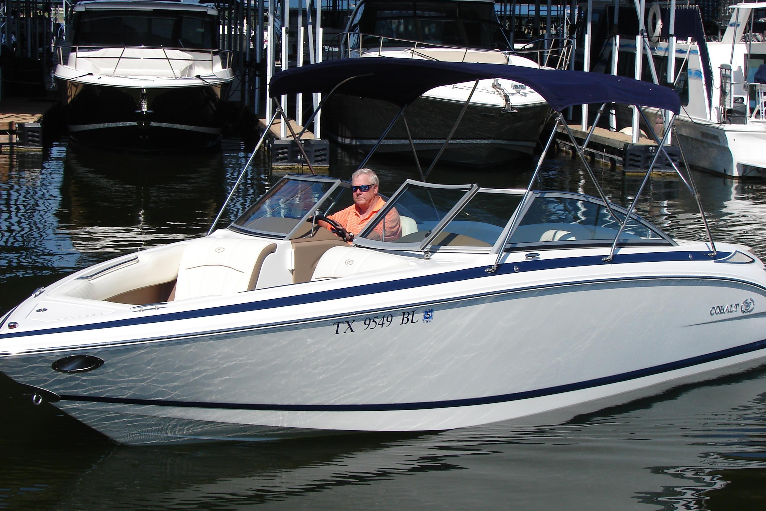 2011 Cobalt 232 boat with canopy, docked in marina, person at helm.