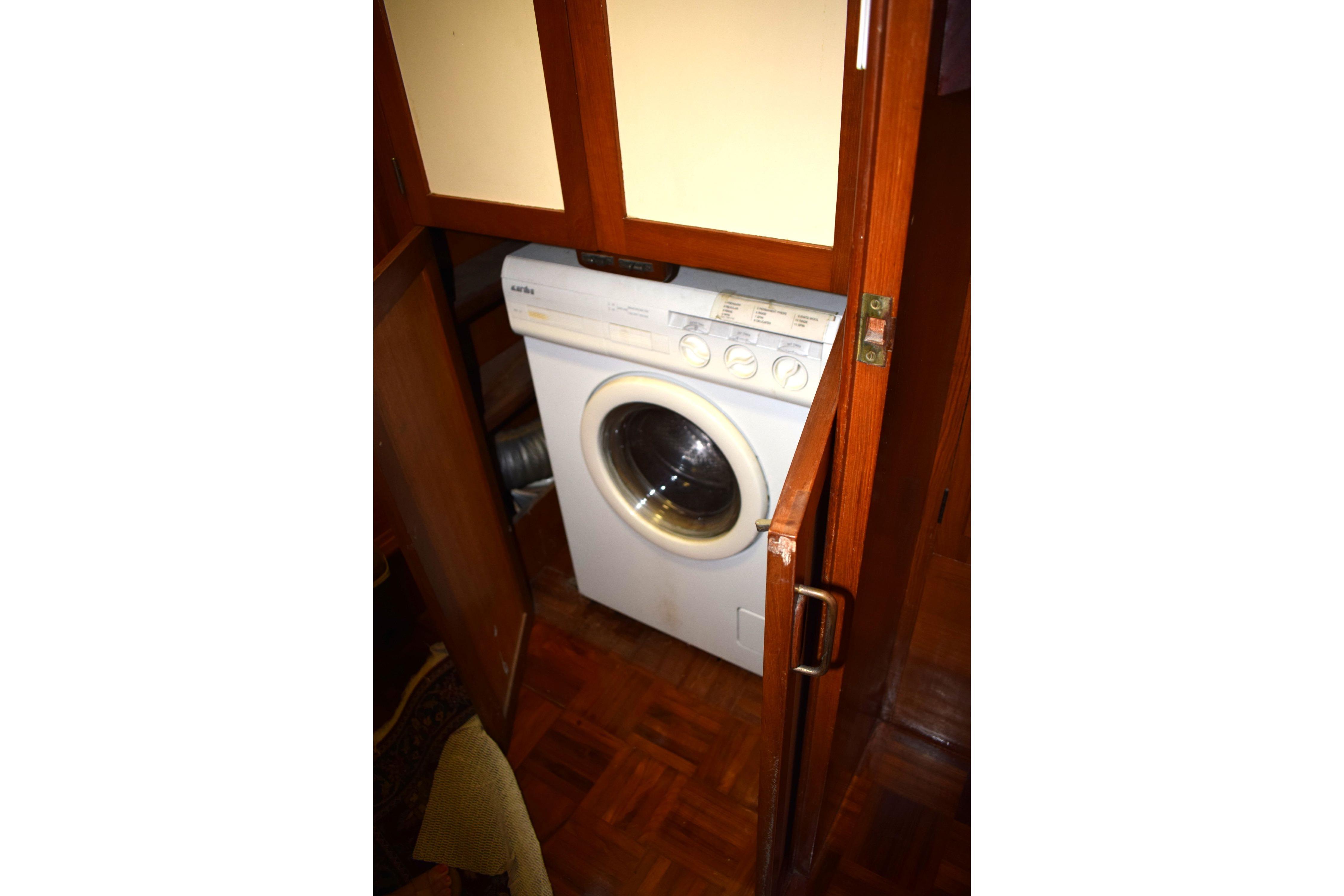 Washing machine inside 1980 Cheoy Lee 52 Motorsailer, wooden cabinetry surrounds appliance.