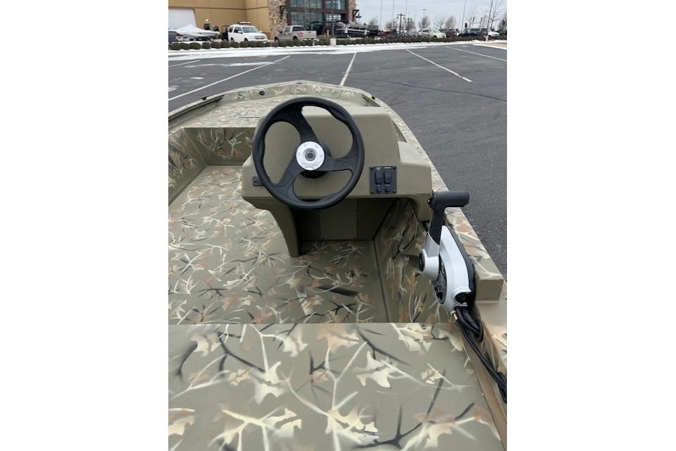 2026 Tracker Grizzly 1648 SC boat with camouflage interior in a parking lot.