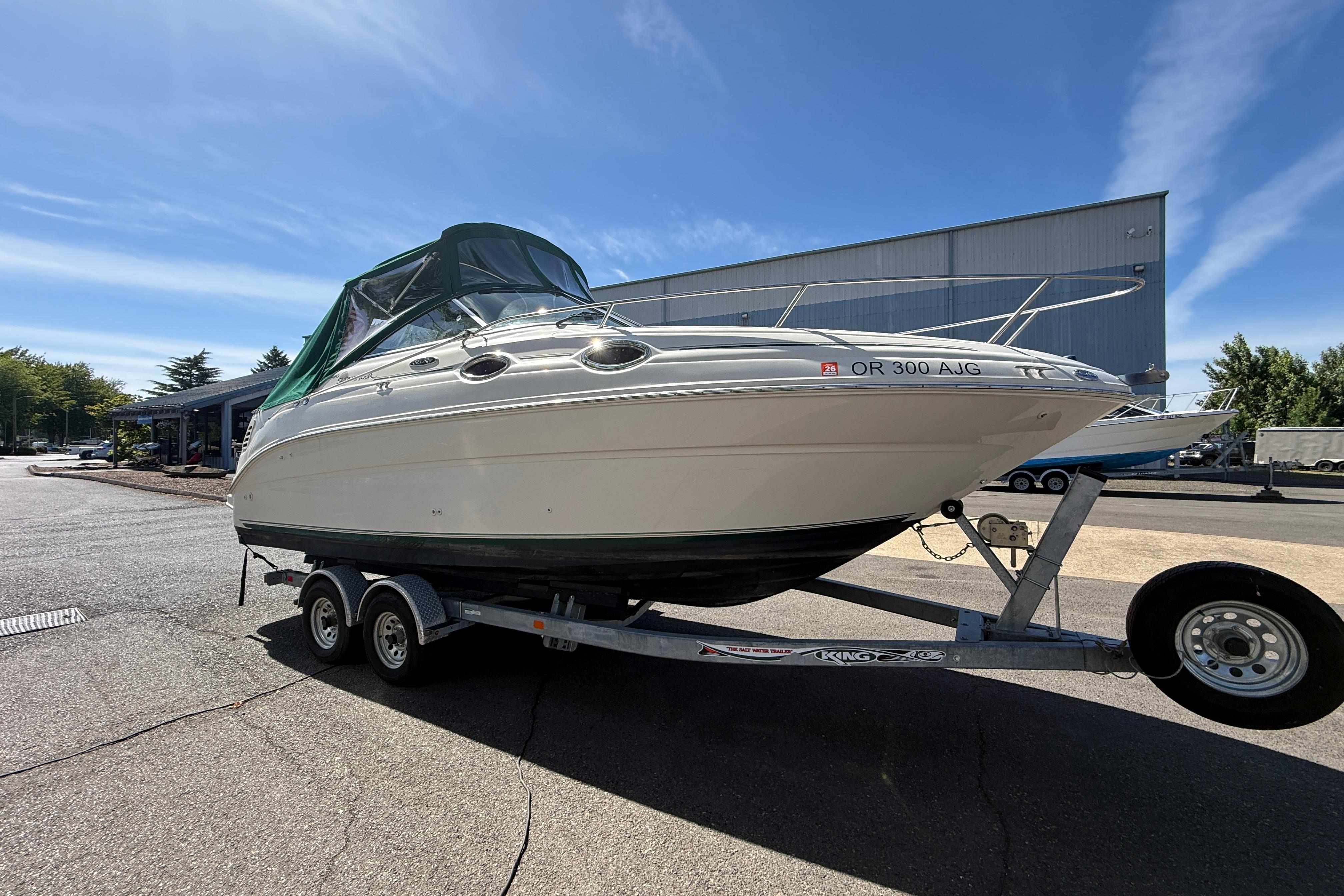 2004 Sea Ray 240 Sundancer boat on trailer, parked outdoors under clear sky.