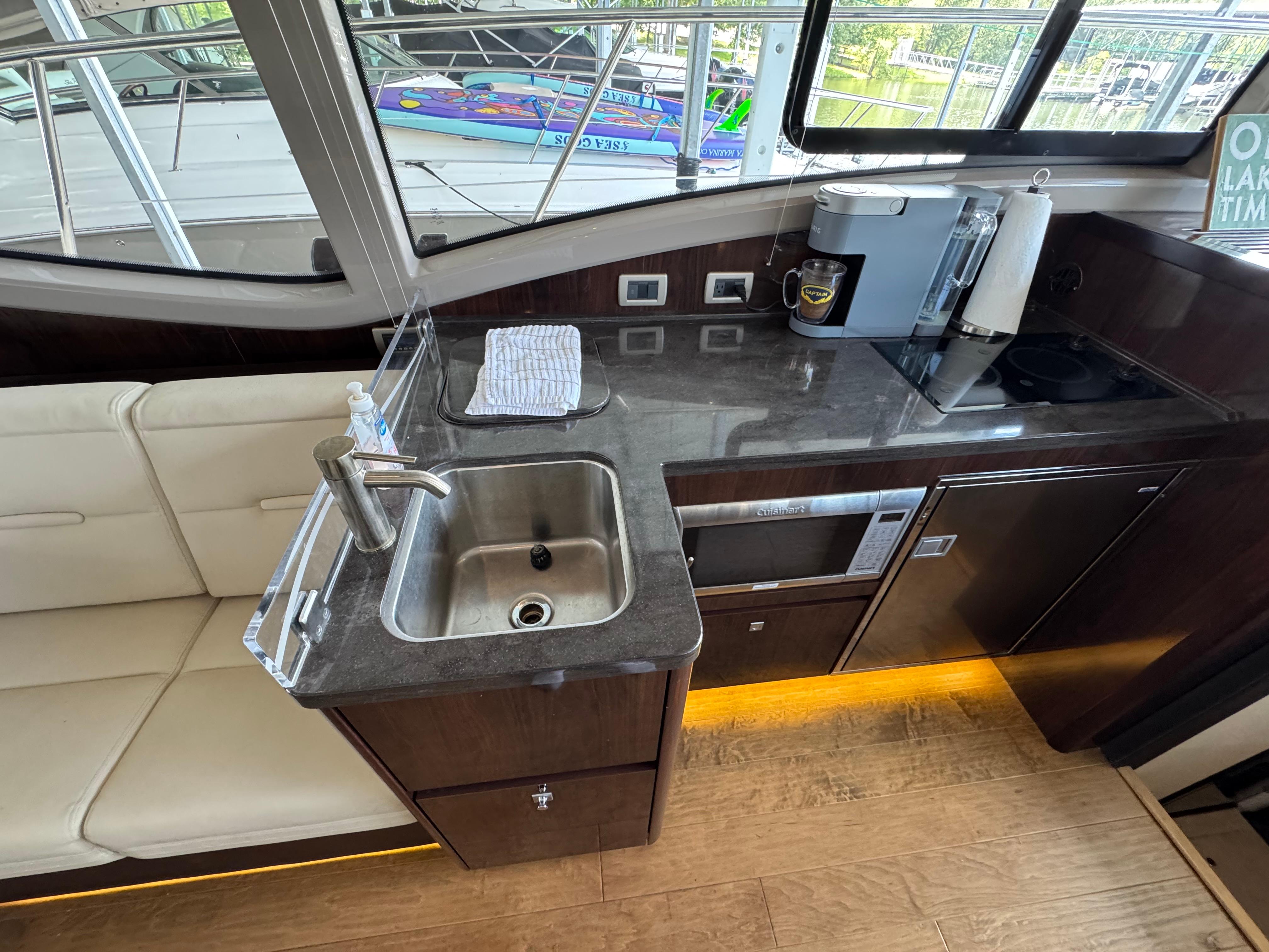 2017 Sea Ray Sundancer 400 yacht interior kitchen with sink, appliances, and seating.