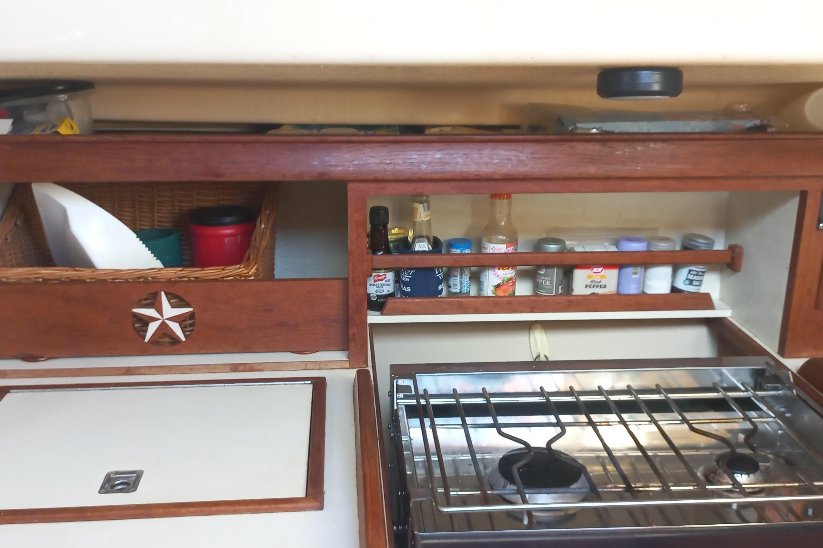 1999 Island Packet 350 yacht kitchen with stove, spice rack, and storage baskets.