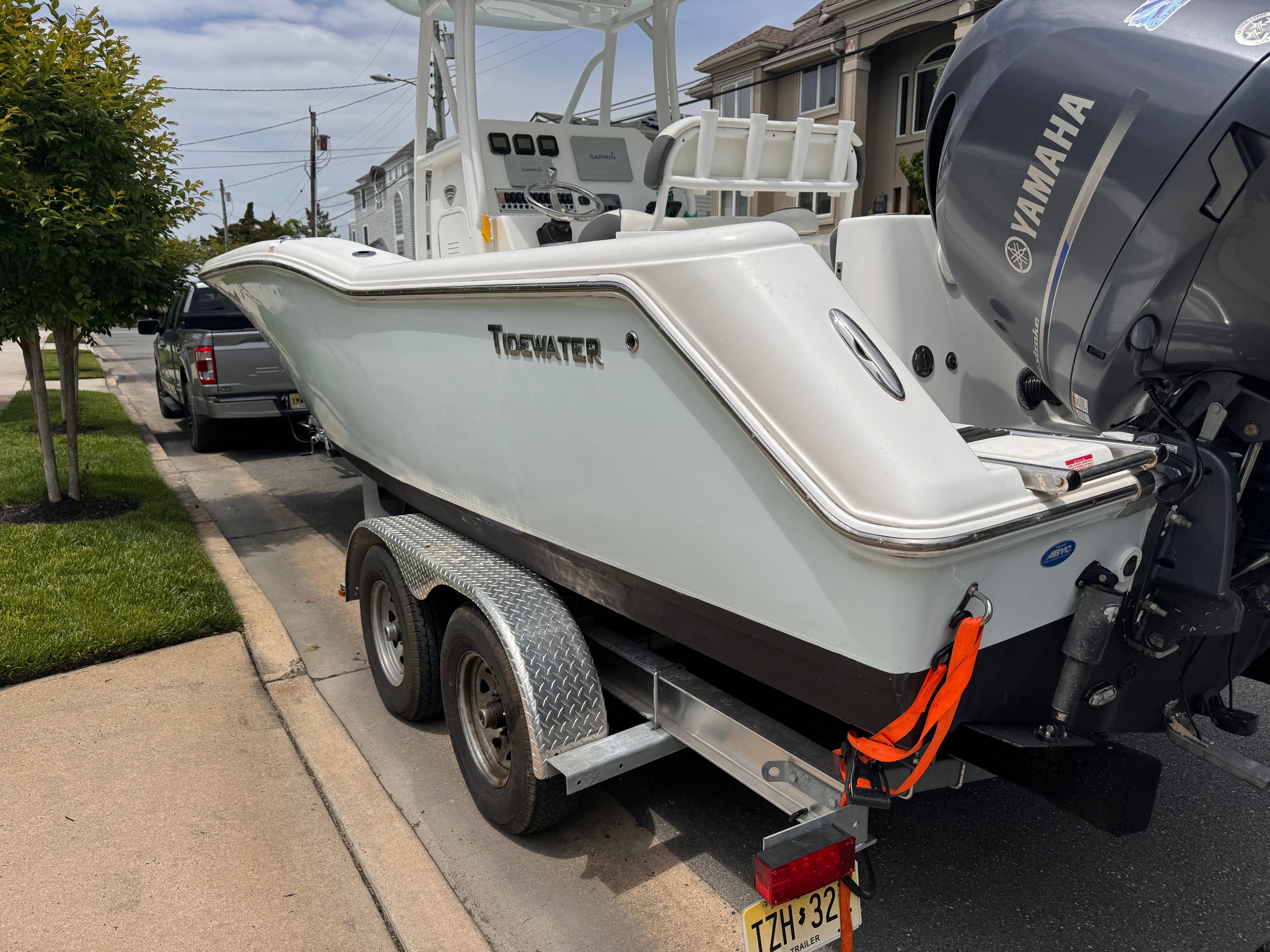 A 2015 Tidewater 250 Adventure boat on a trailer, parked on a residential street.