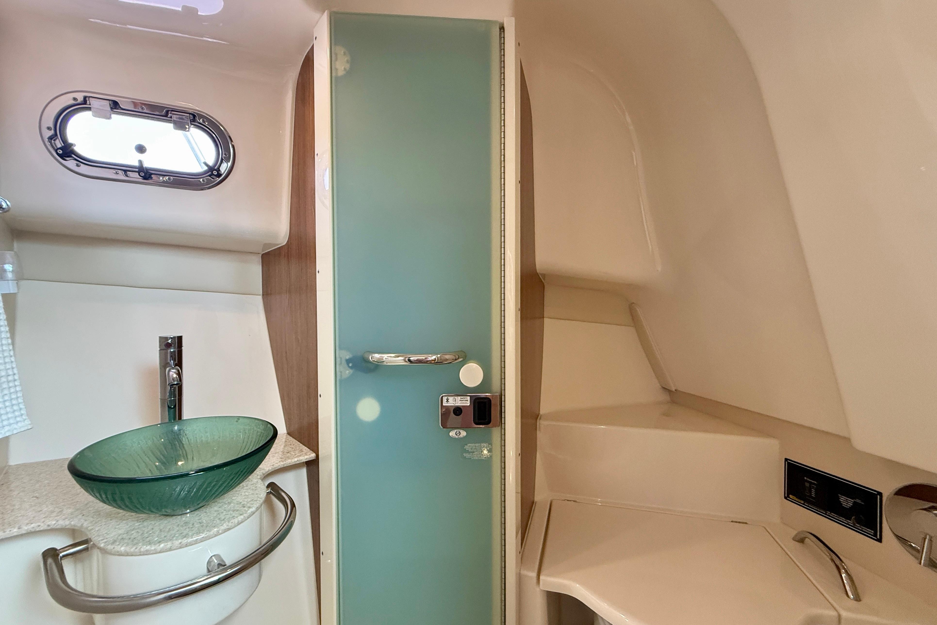 2012 Pursuit OS 345 Offshore boat bathroom with glass sink and frosted door.