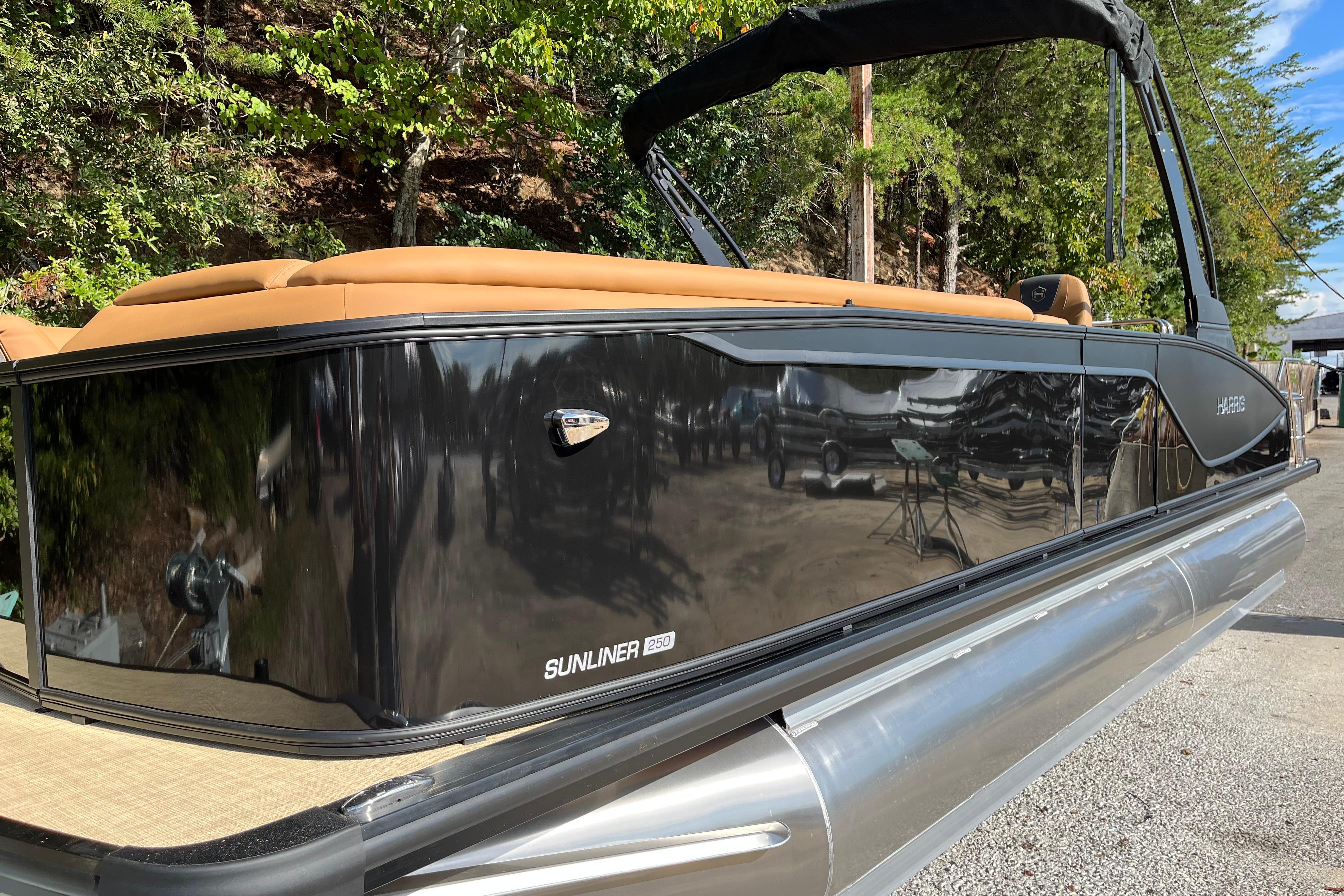 2025 Harris Sunliner 250 pontoon boat with sleek black exterior and tan seating.