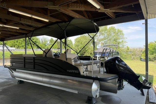 2025 Harris Sunliner 230 pontoon boat under shelter, featuring sleek design and modern amenities.