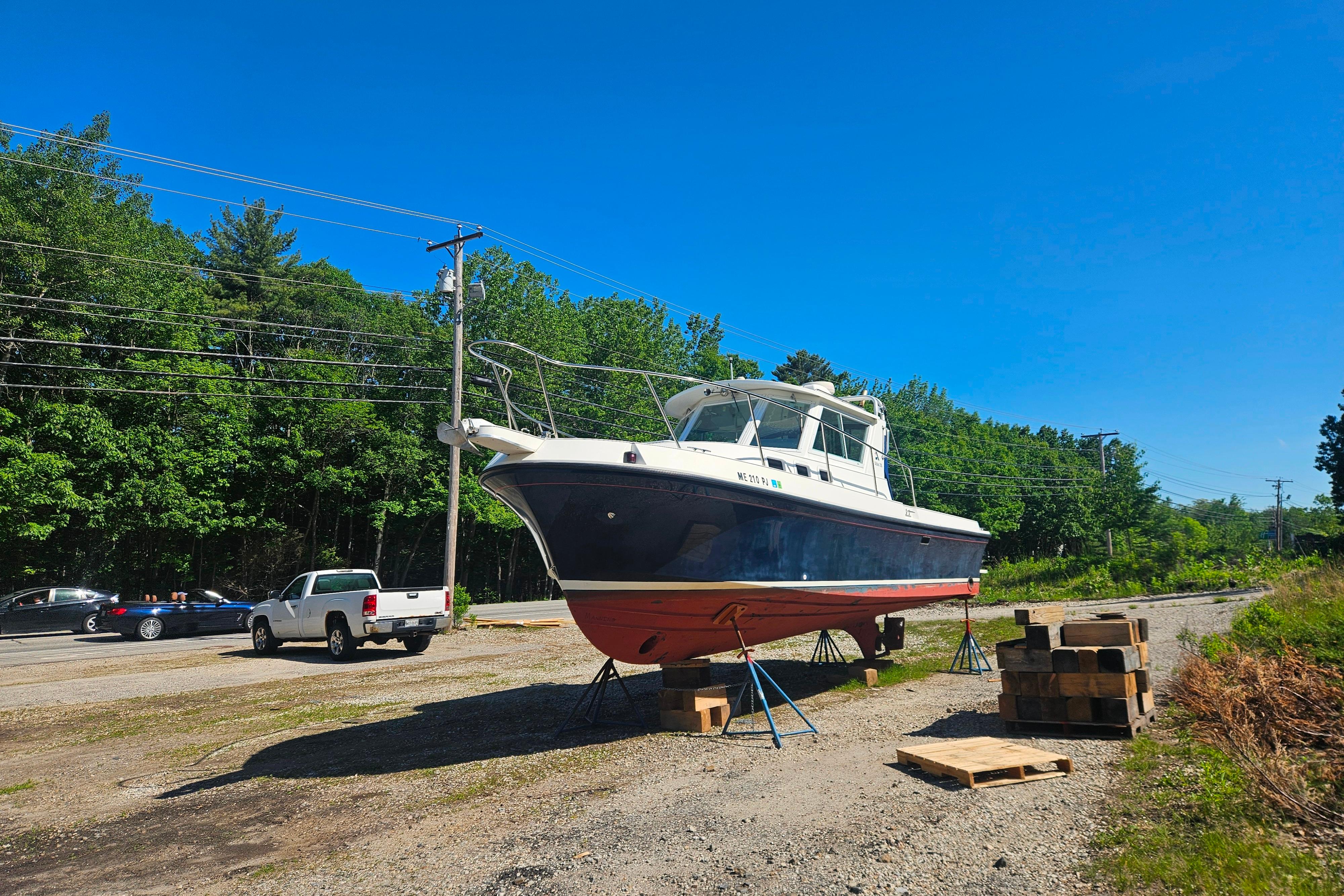 1999 Albin 28 Tournament Express boat on stands, surrounded by trees and vehicles.