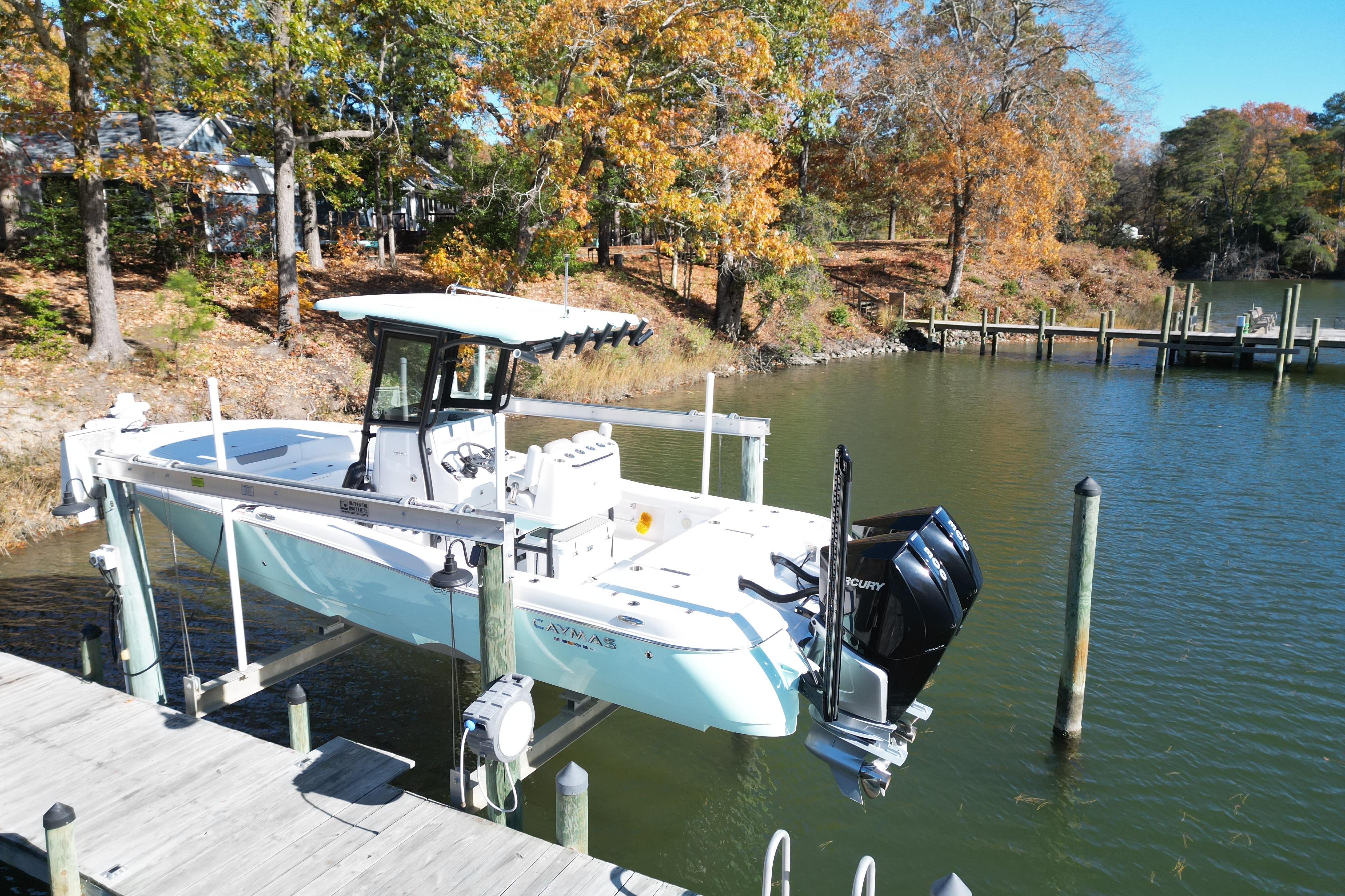 2023 Caymas 281 HB boat on lift by autumn trees and calm water.