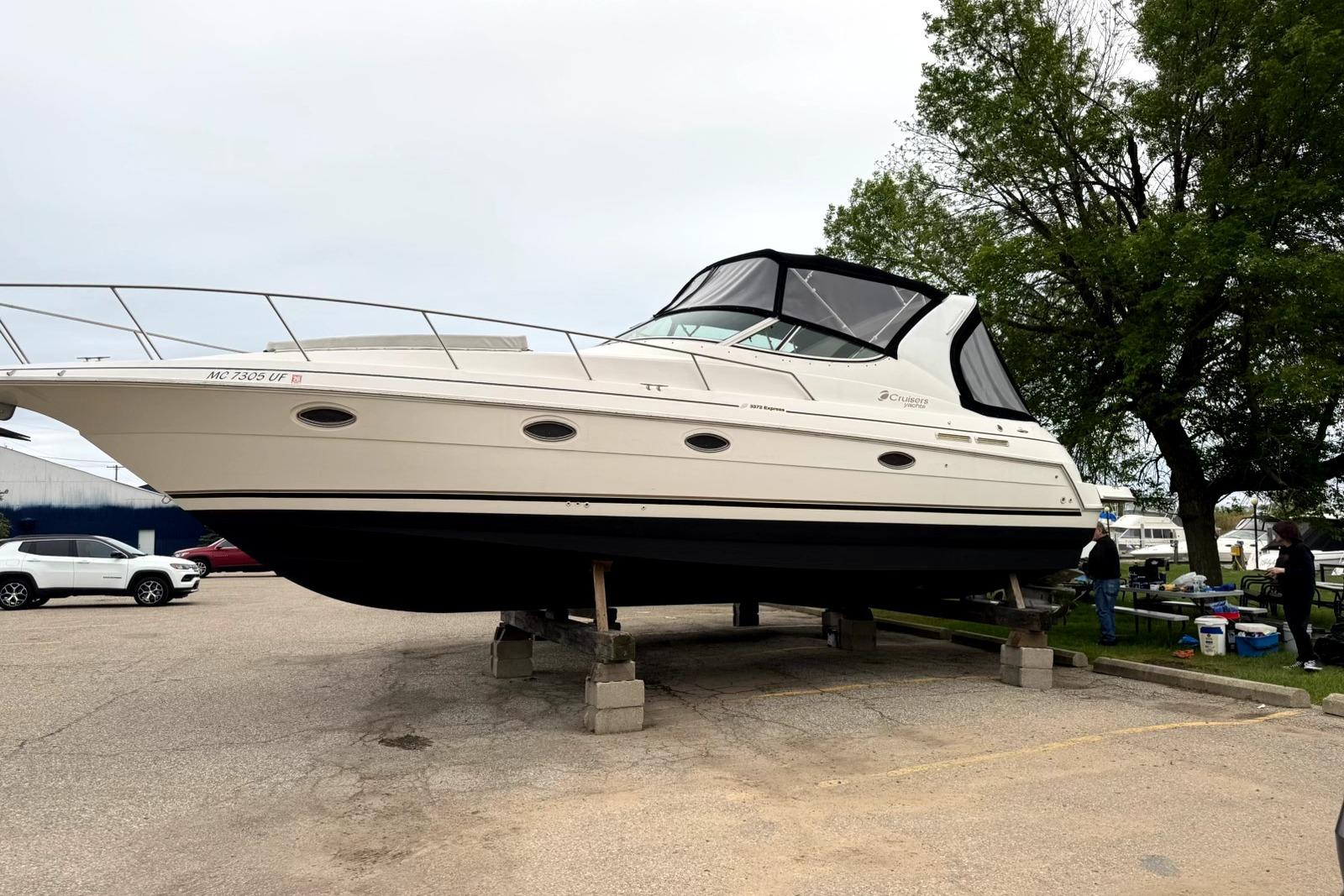 2004 Cruisers Yachts 3372 Express boat on blocks in a parking area.