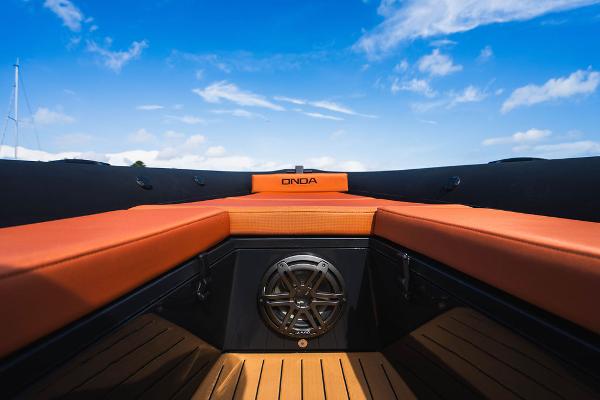 2024 Onda Magna boat interior with orange seating and blue sky background.