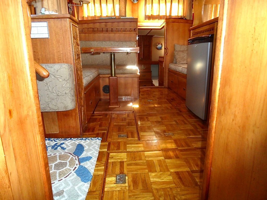 Interior of a 1976 CHB Trawler with wooden flooring and cozy seating area.