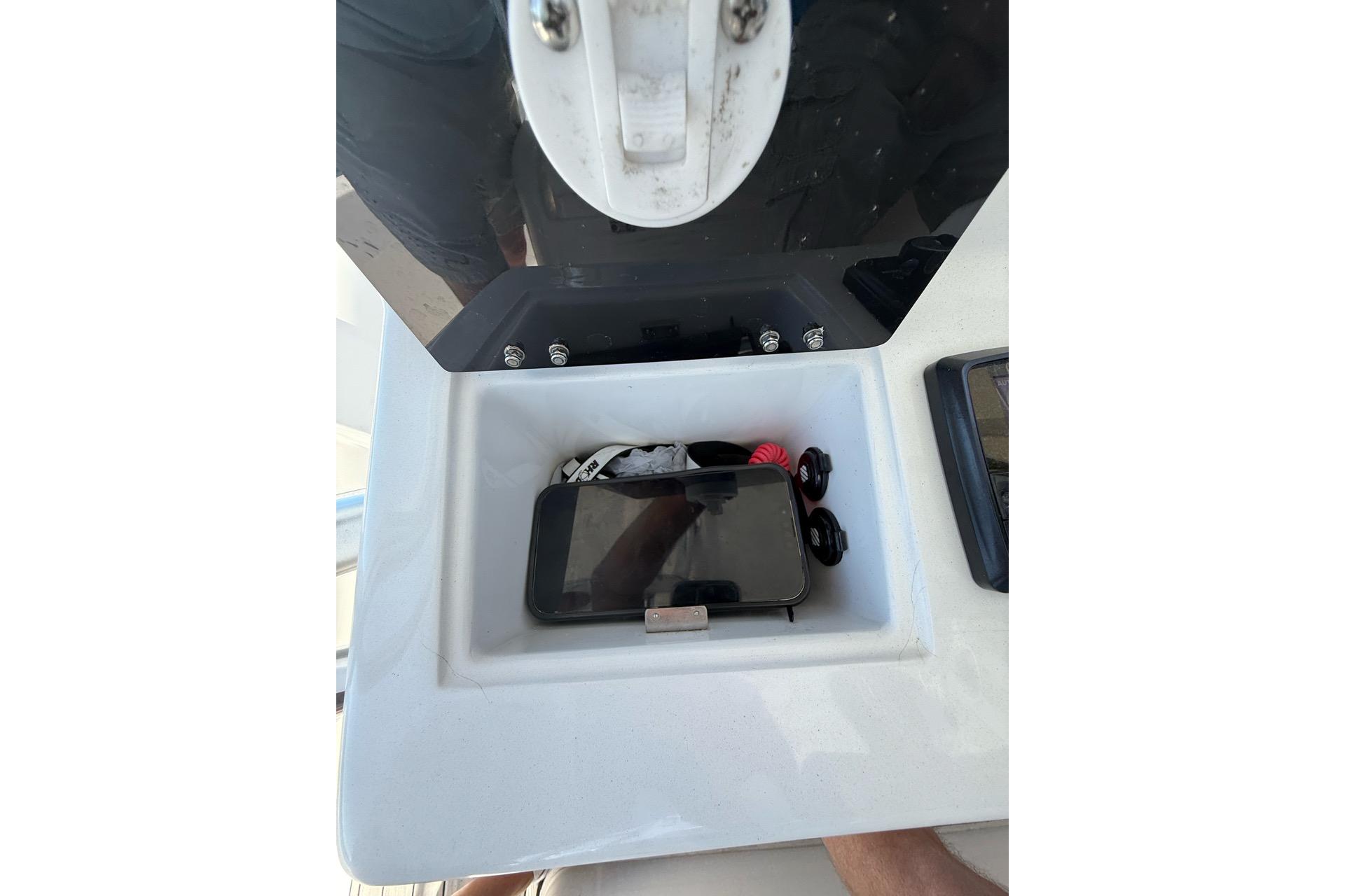Storage compartment on 2021 Custom Infusion 34 CC boat with phone and accessories.