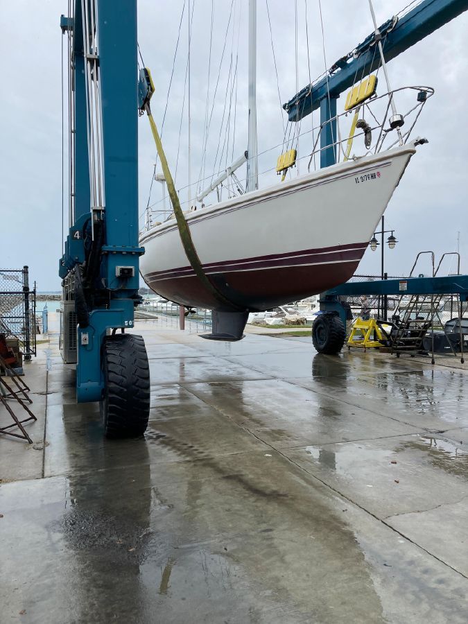 A Catalina 42 Tricabin sailboat being lifted out of the water by a crane.