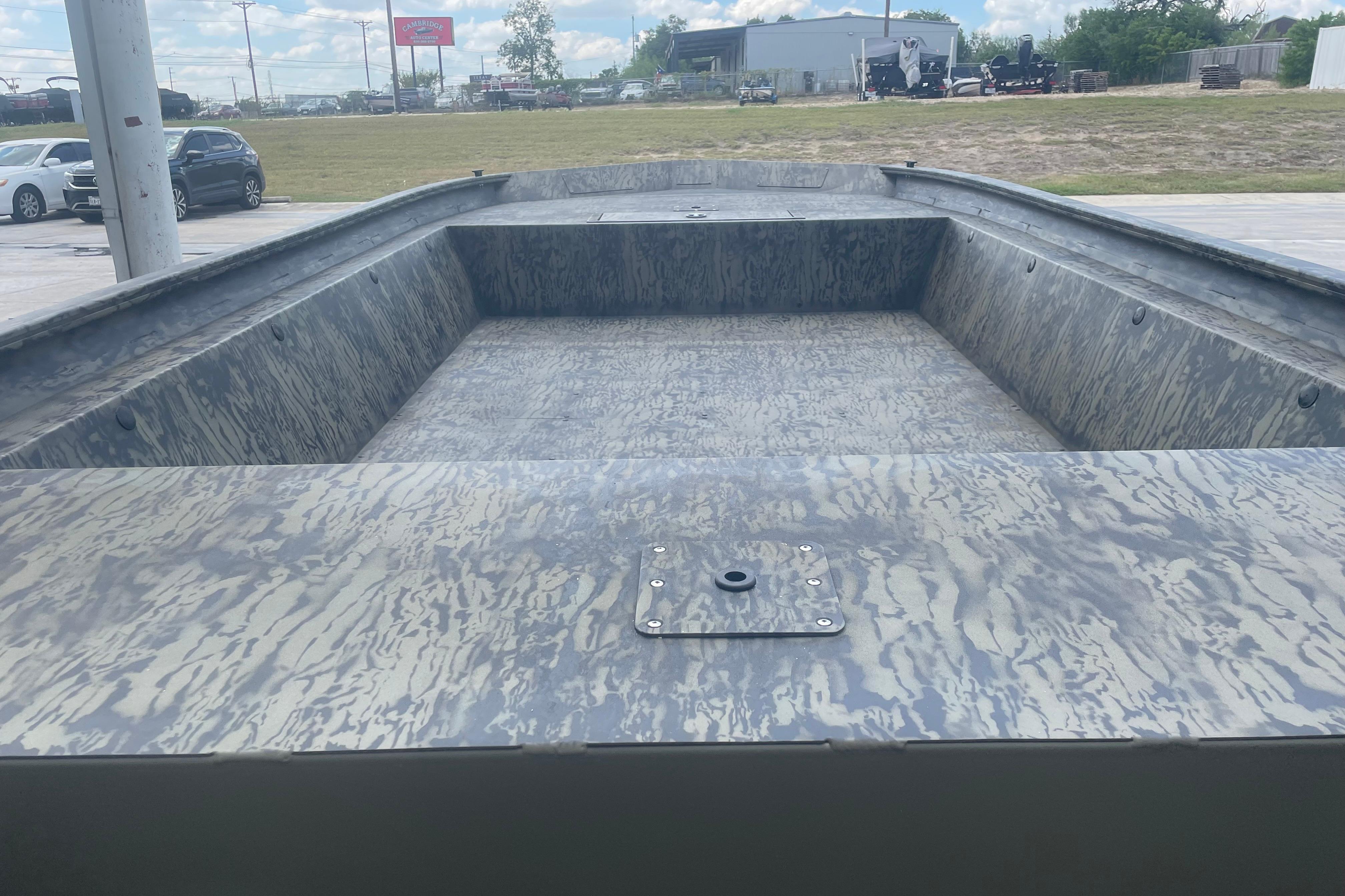 2026 Tracker Grizzly 1860 Utility boat interior with camouflage pattern, parked outdoors.