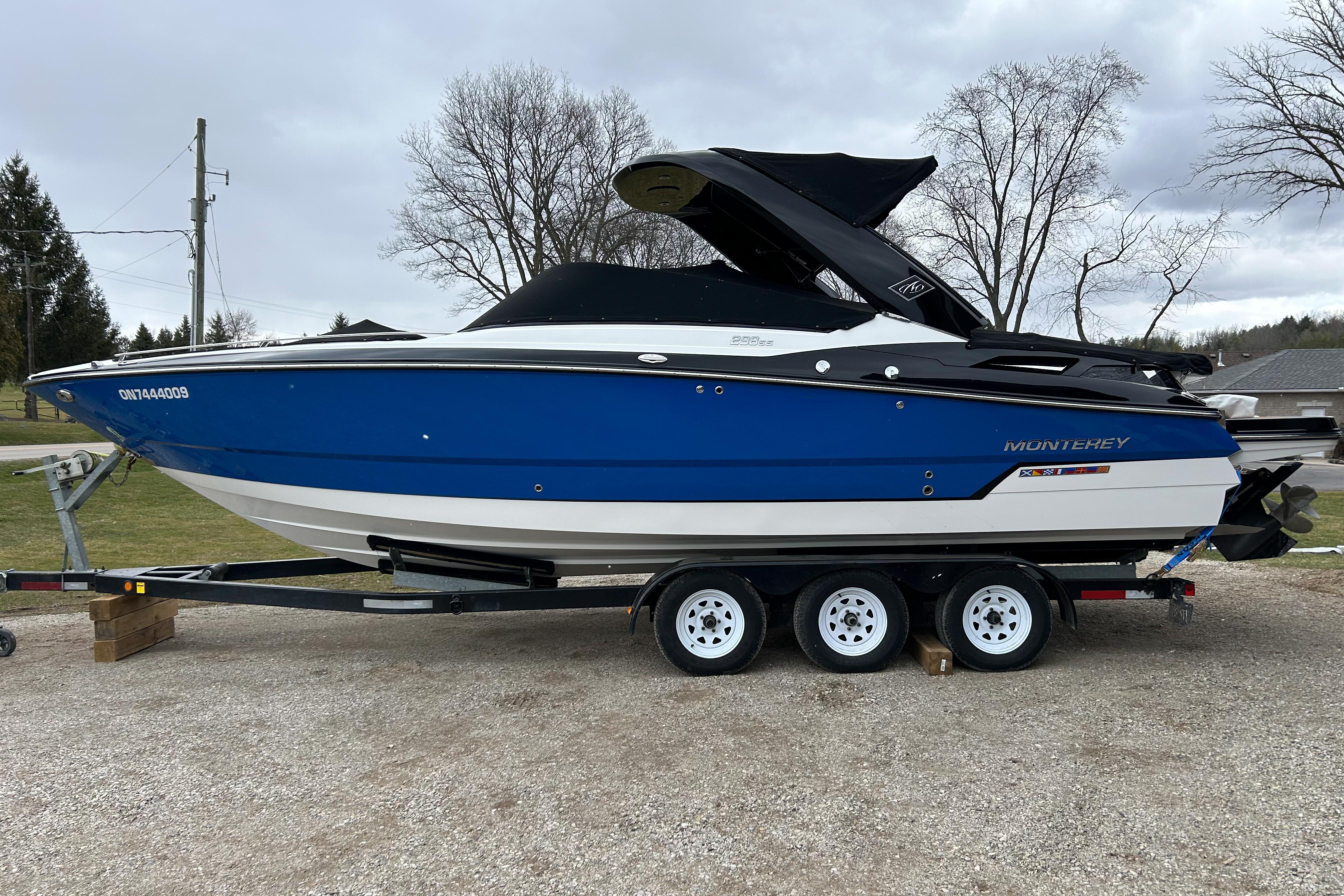 2018 Monterey 298SS Super Sport boat on trailer, blue and white design, parked outdoors.