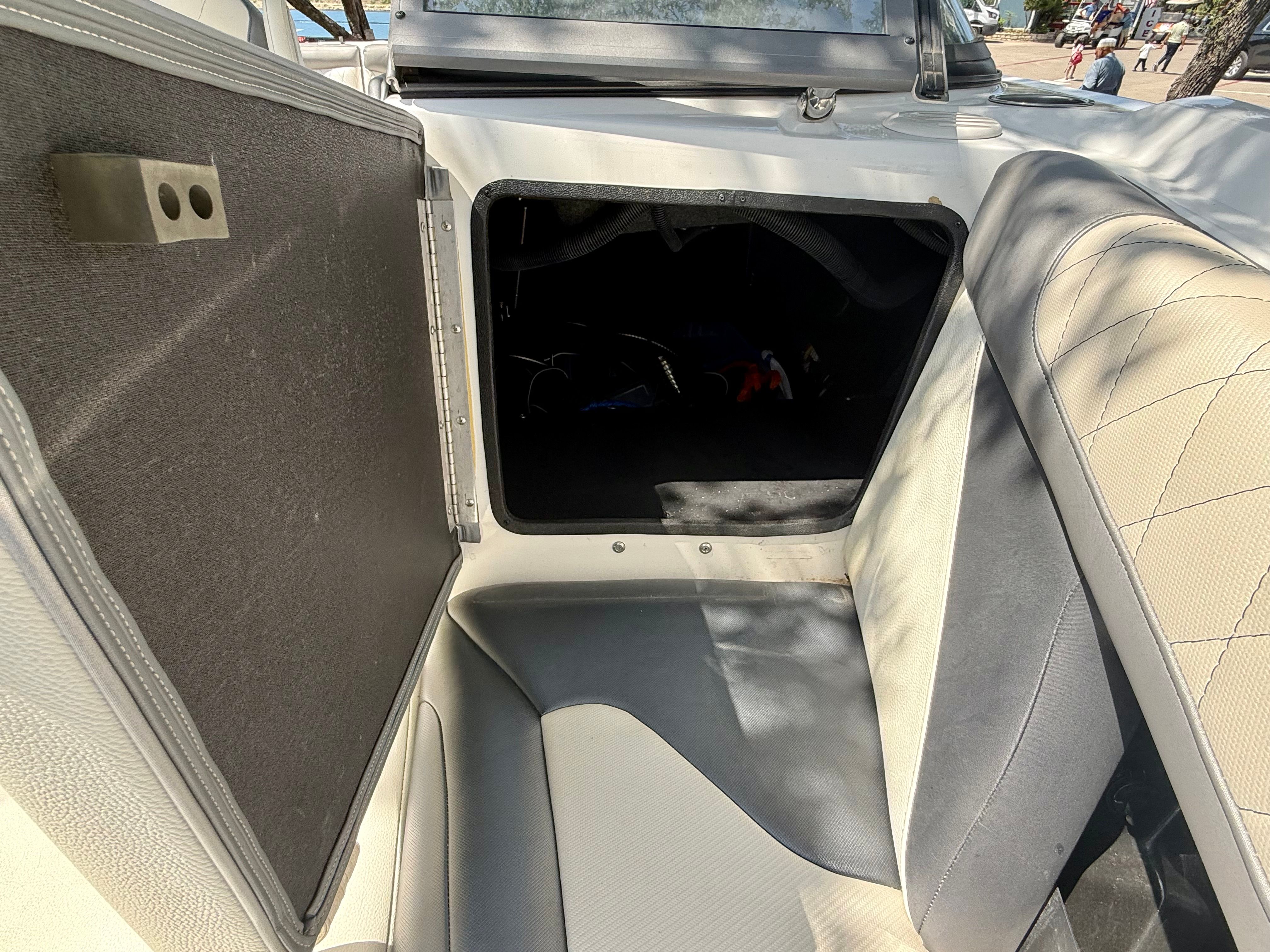 An open storage compartment inside a boat with gray and white upholstery.