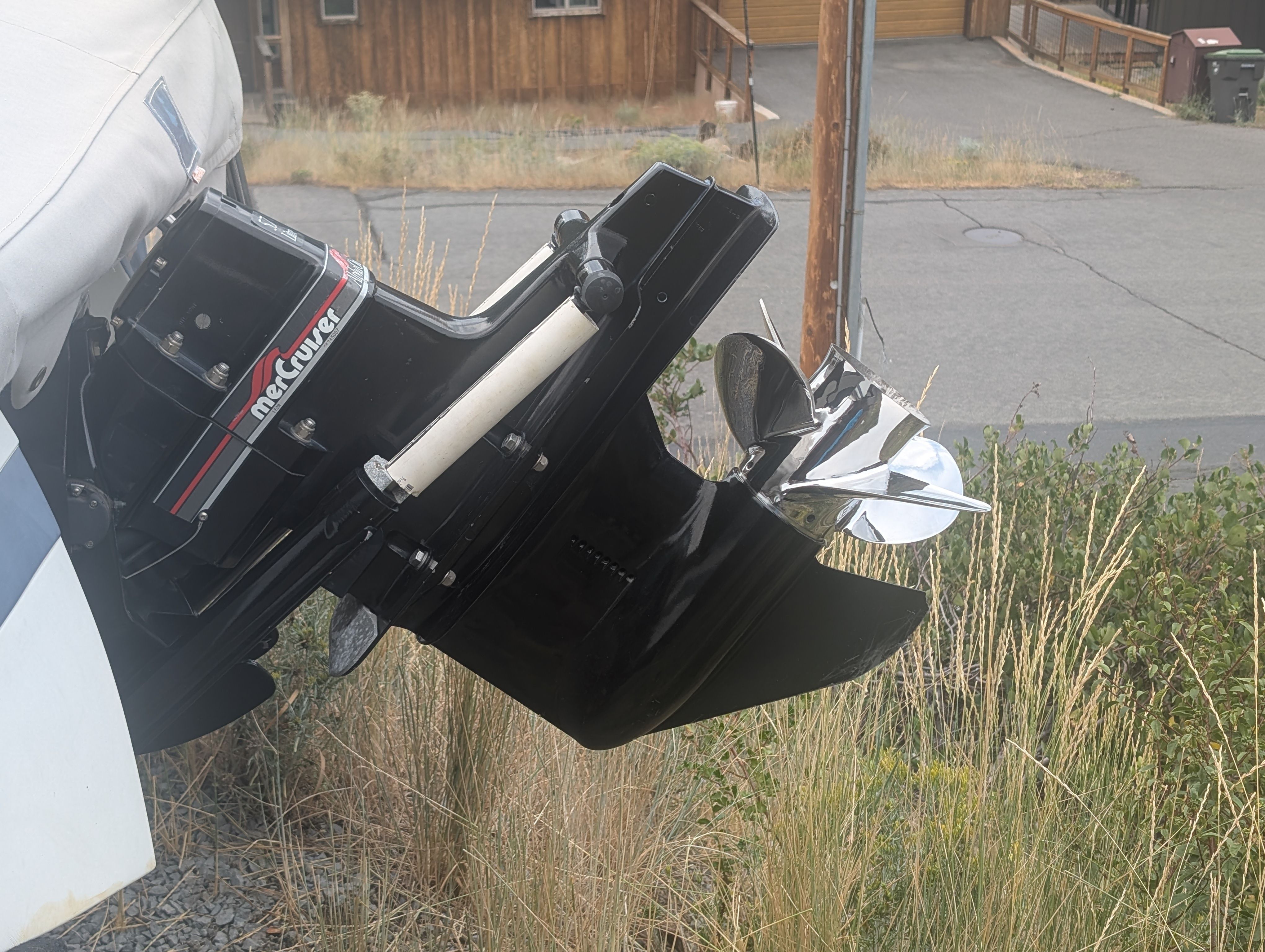 A 1997 Cobalt 190 boat with a shiny outboard motor and propeller, parked on dry grass.
