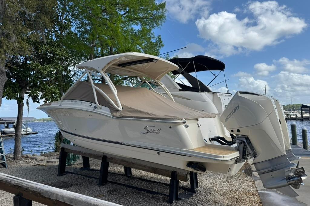 2024 Scout 255 Dorado boat with Mercury engine docked by a lake.