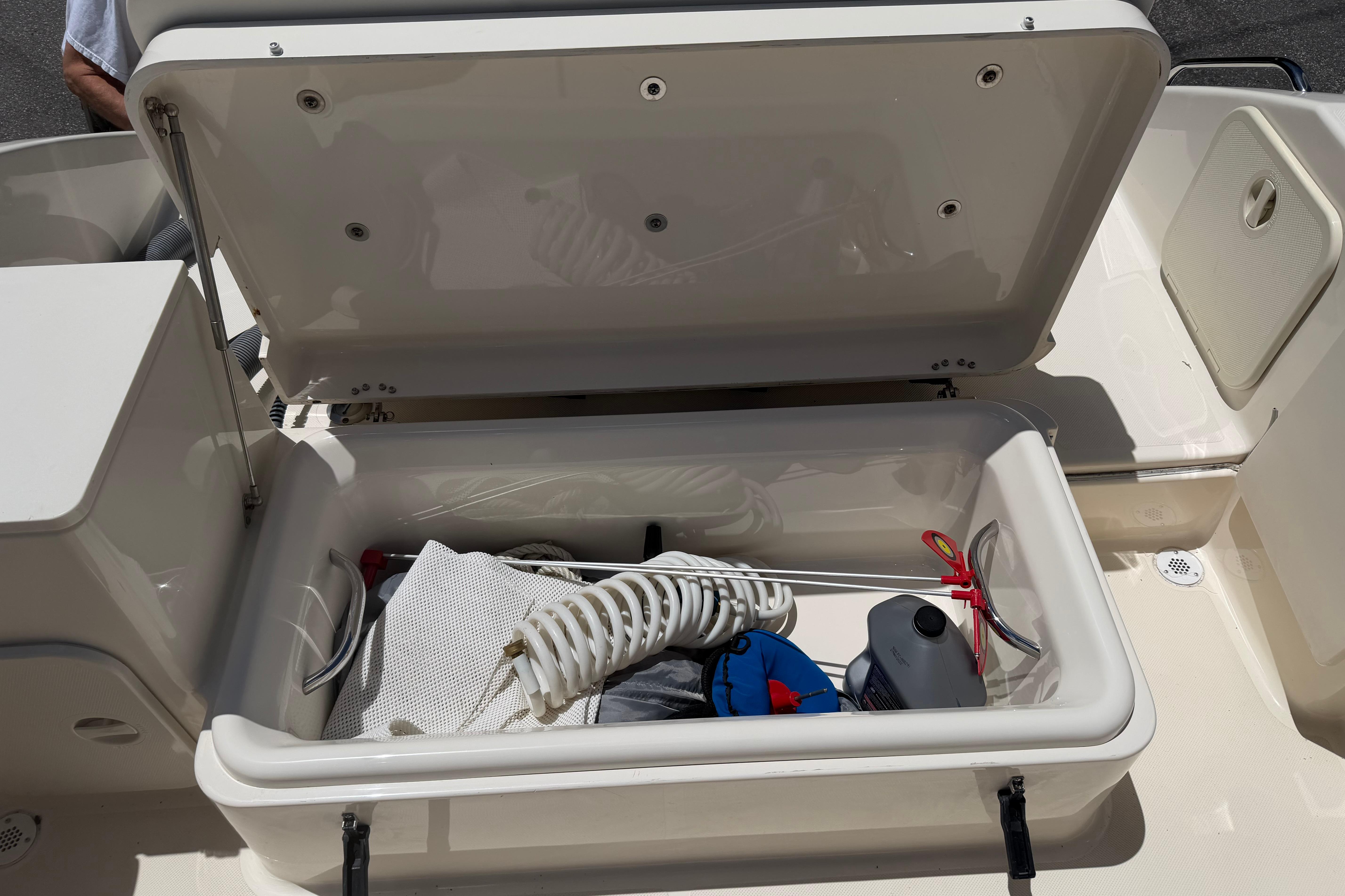 Open storage compartment on 2010 Pursuit OS 255 Offshore boat, containing coiled rope and equipment.