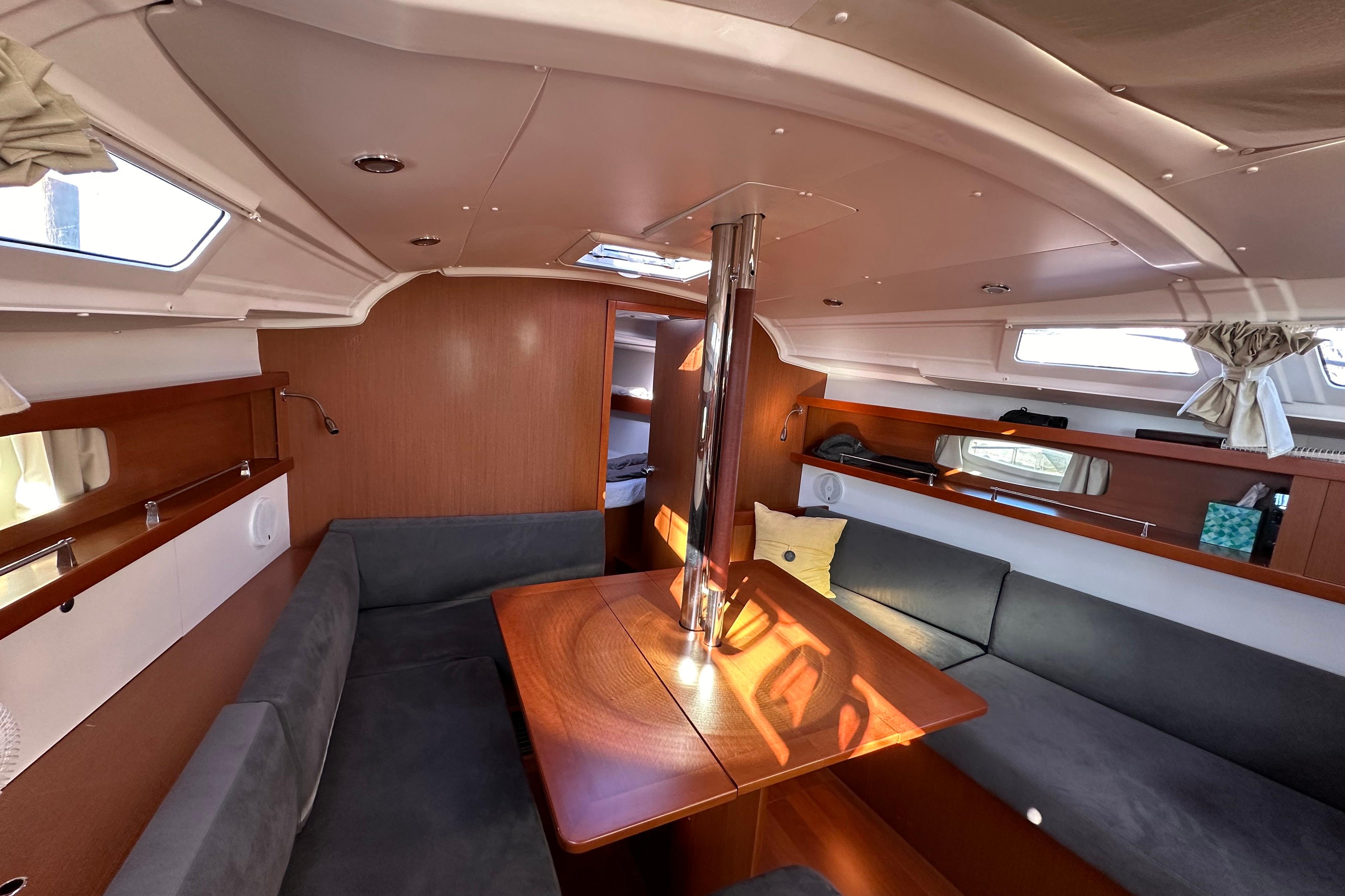 2015 Beneteau Oceanis 37 interior with cozy seating and wooden table.