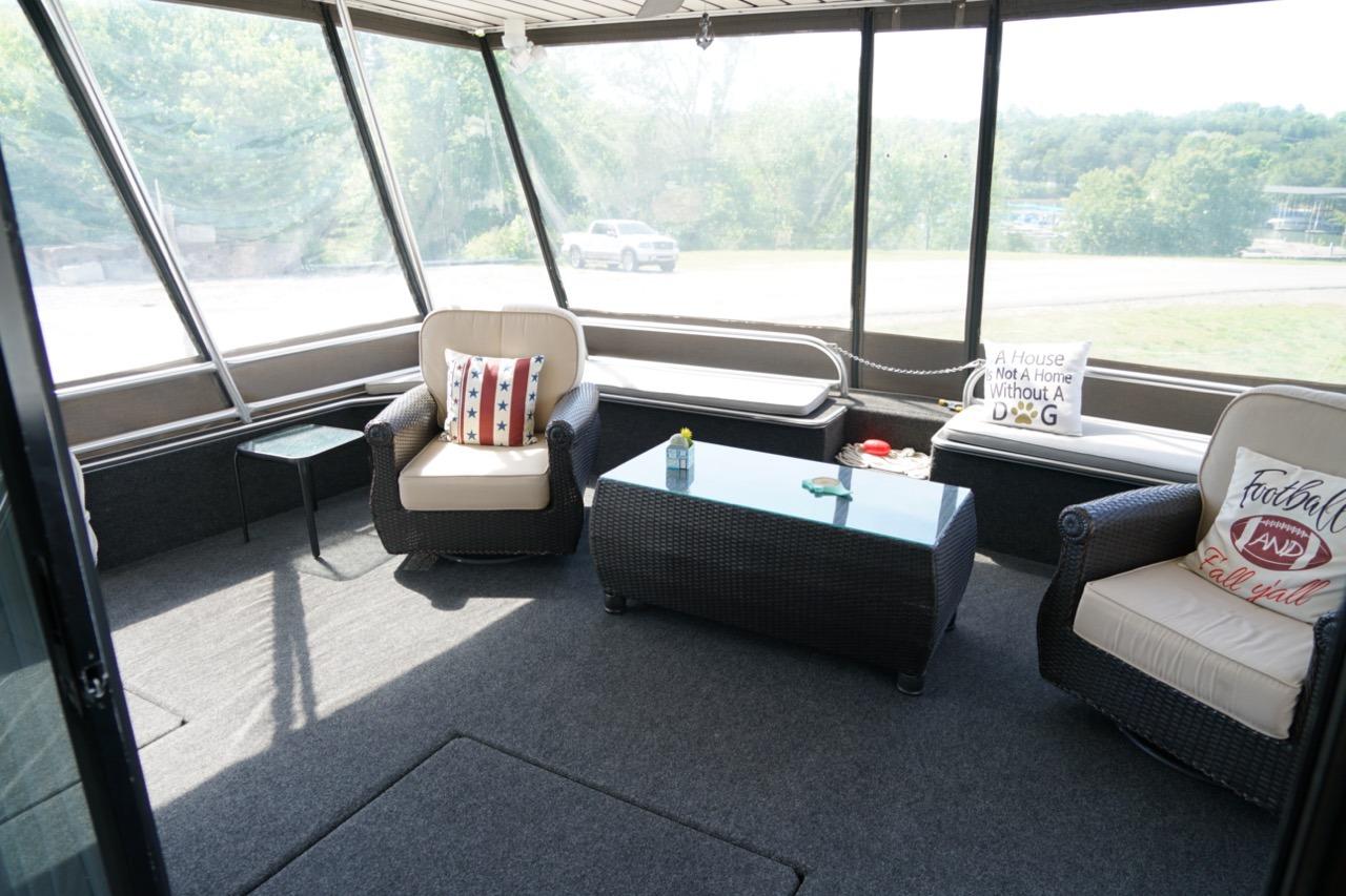Spacious sunroom on 2000 Stardust Cruisers houseboat with cozy seating and decorative pillows.