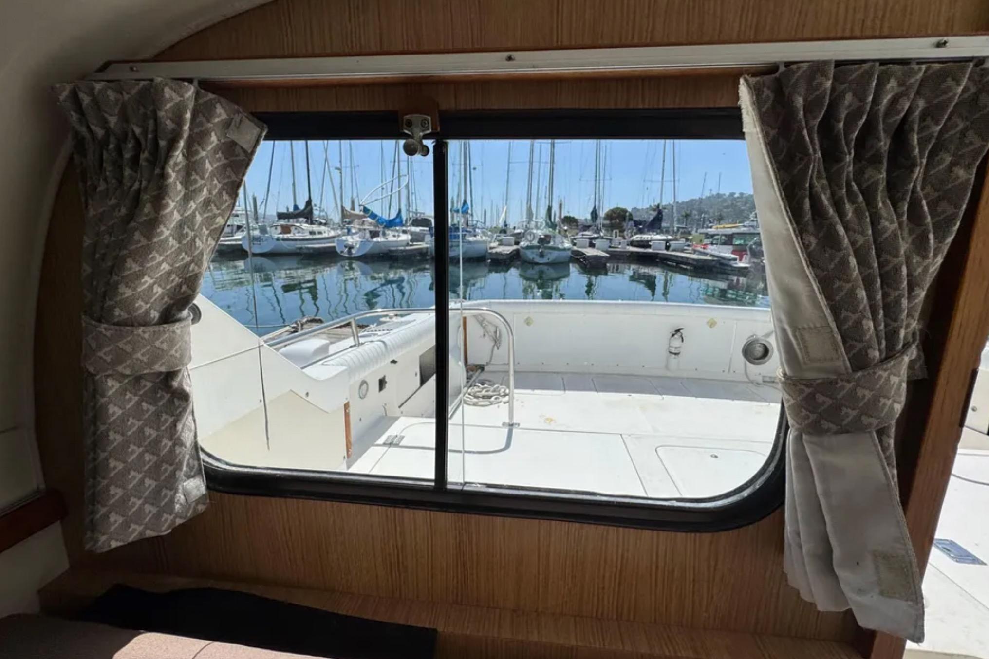 Interior view from a 1988 Bertram 28 Sport Fisherman, overlooking a marina through a window.