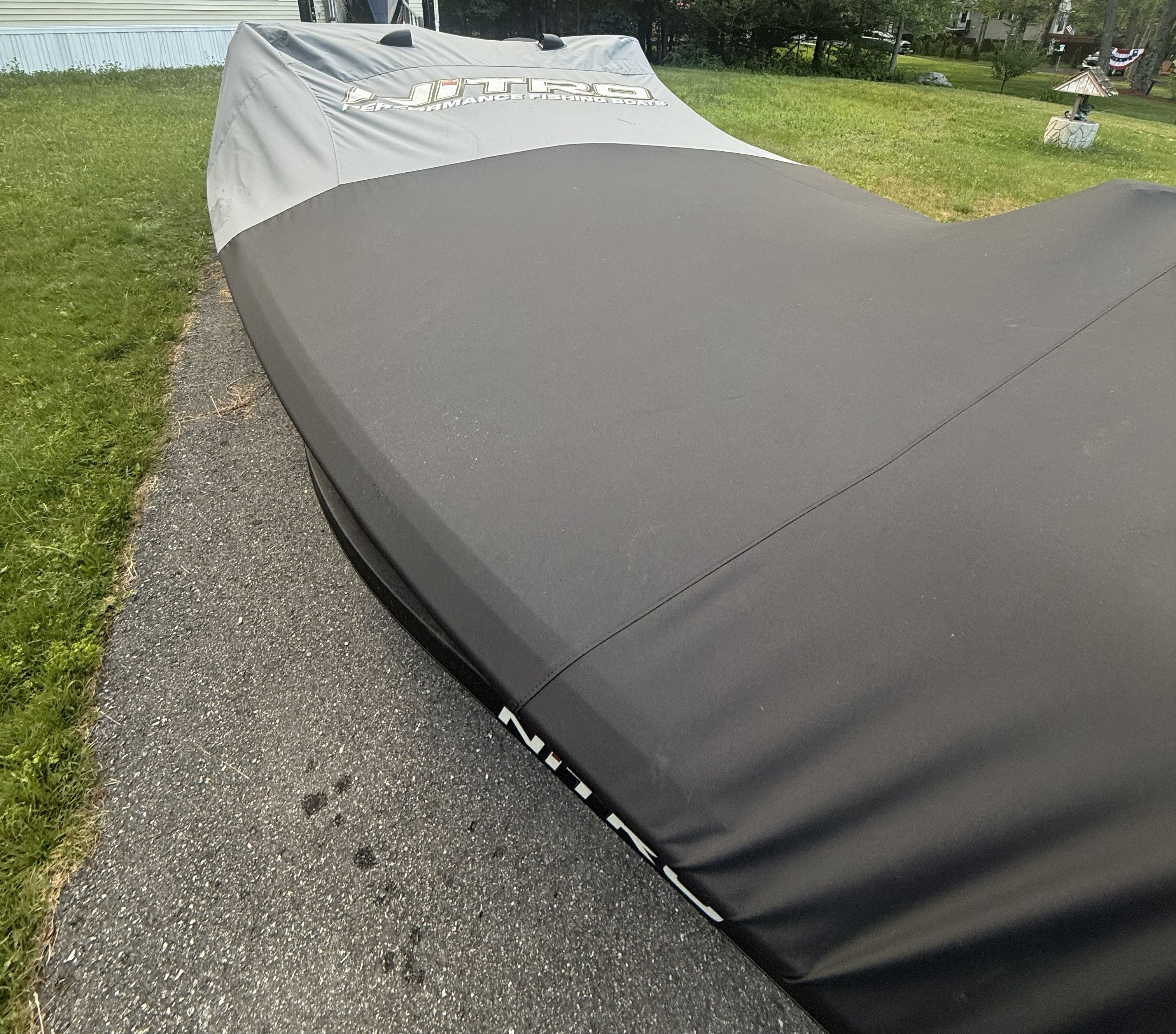 A 2023 Nitro Z21 XL Pro boat with a gray cover on a paved path.