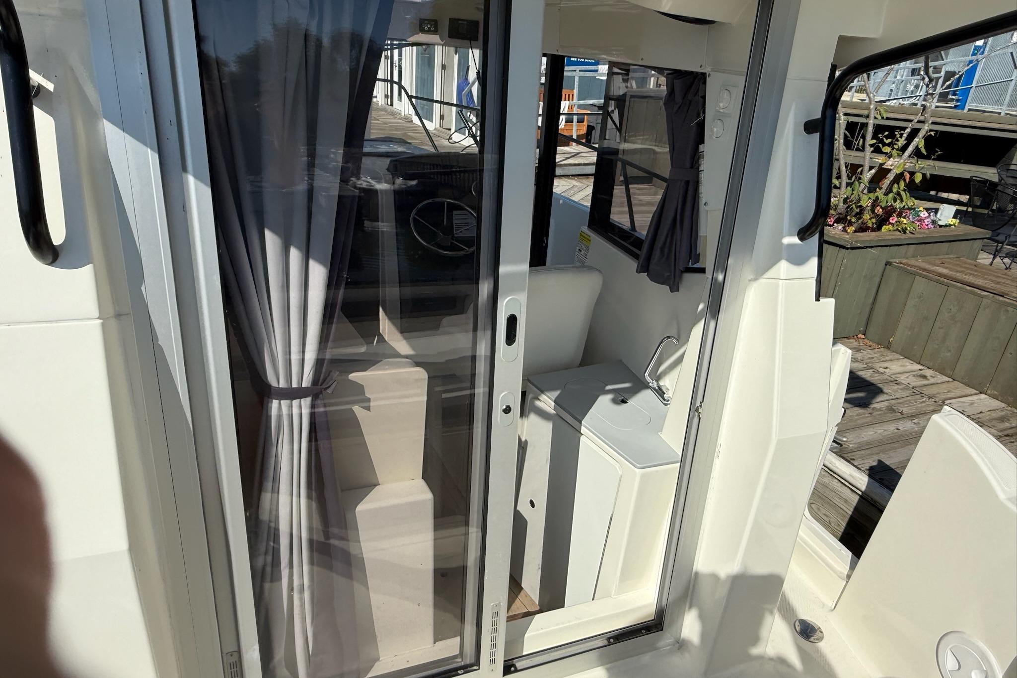 2024 Bayliner Trophy T25 Pilothouse interior with sliding door and compact sink.