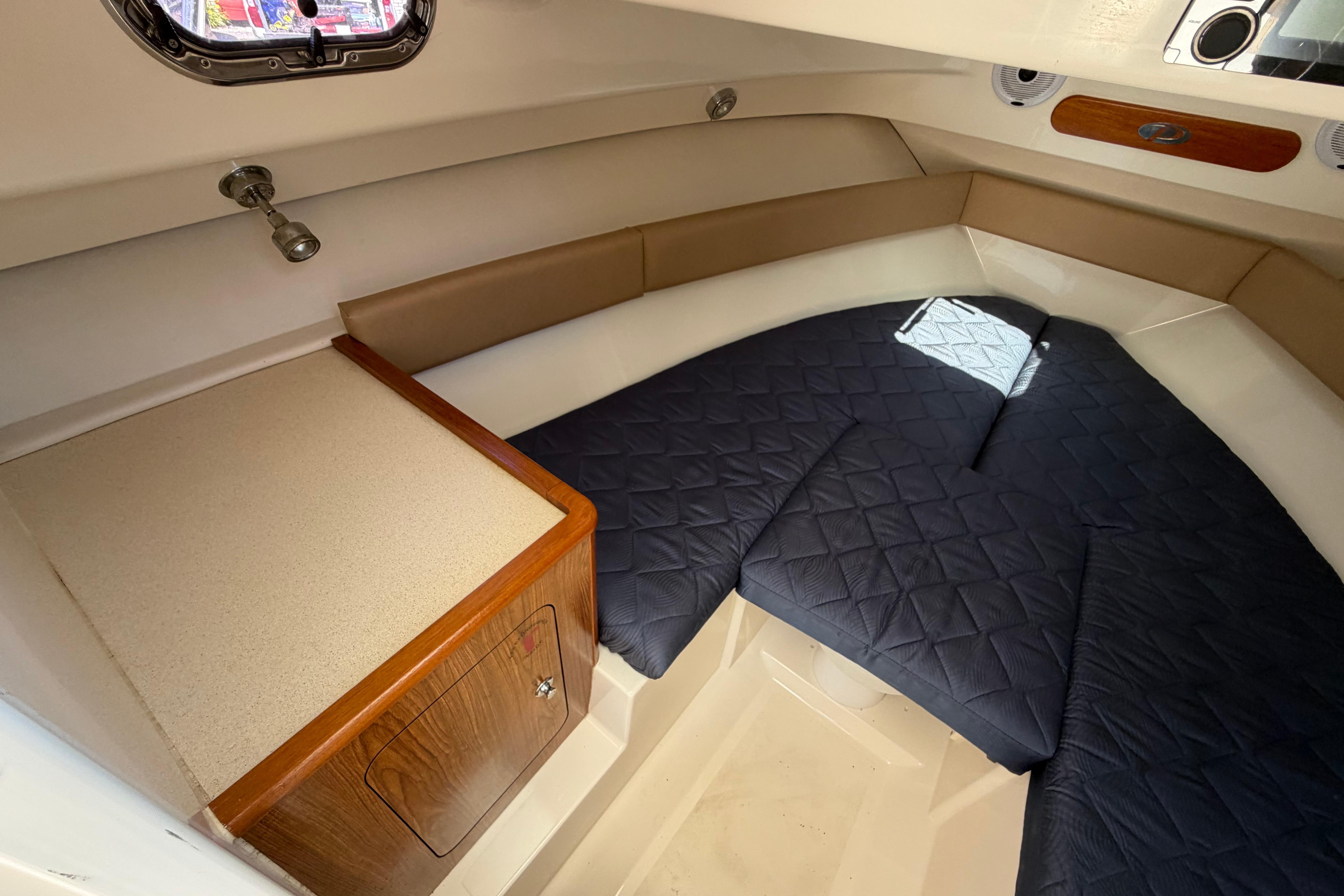 2010 Pursuit OS 255 Offshore cabin interior with cushioned seating and wooden storage.
