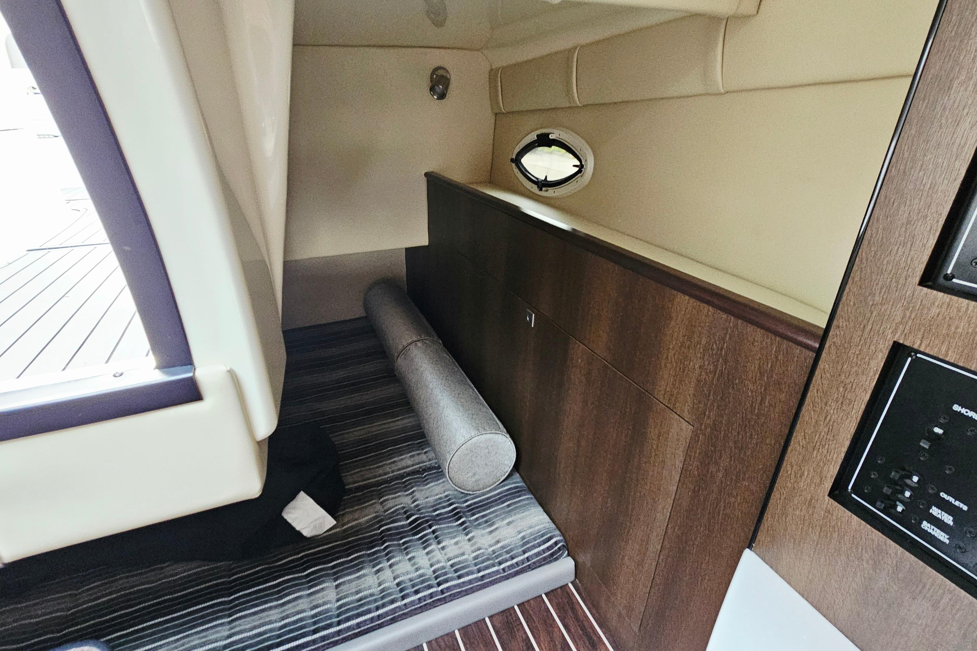 Interior cabin of 2016 Monterey 295 Sport Yacht with wood paneling and striped flooring.
