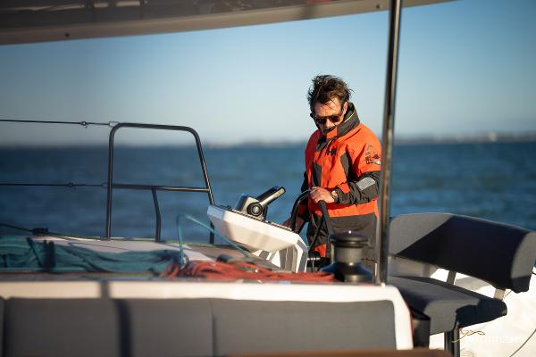 Man steering 2025 Nautitech 48 Open catamaran on open sea.