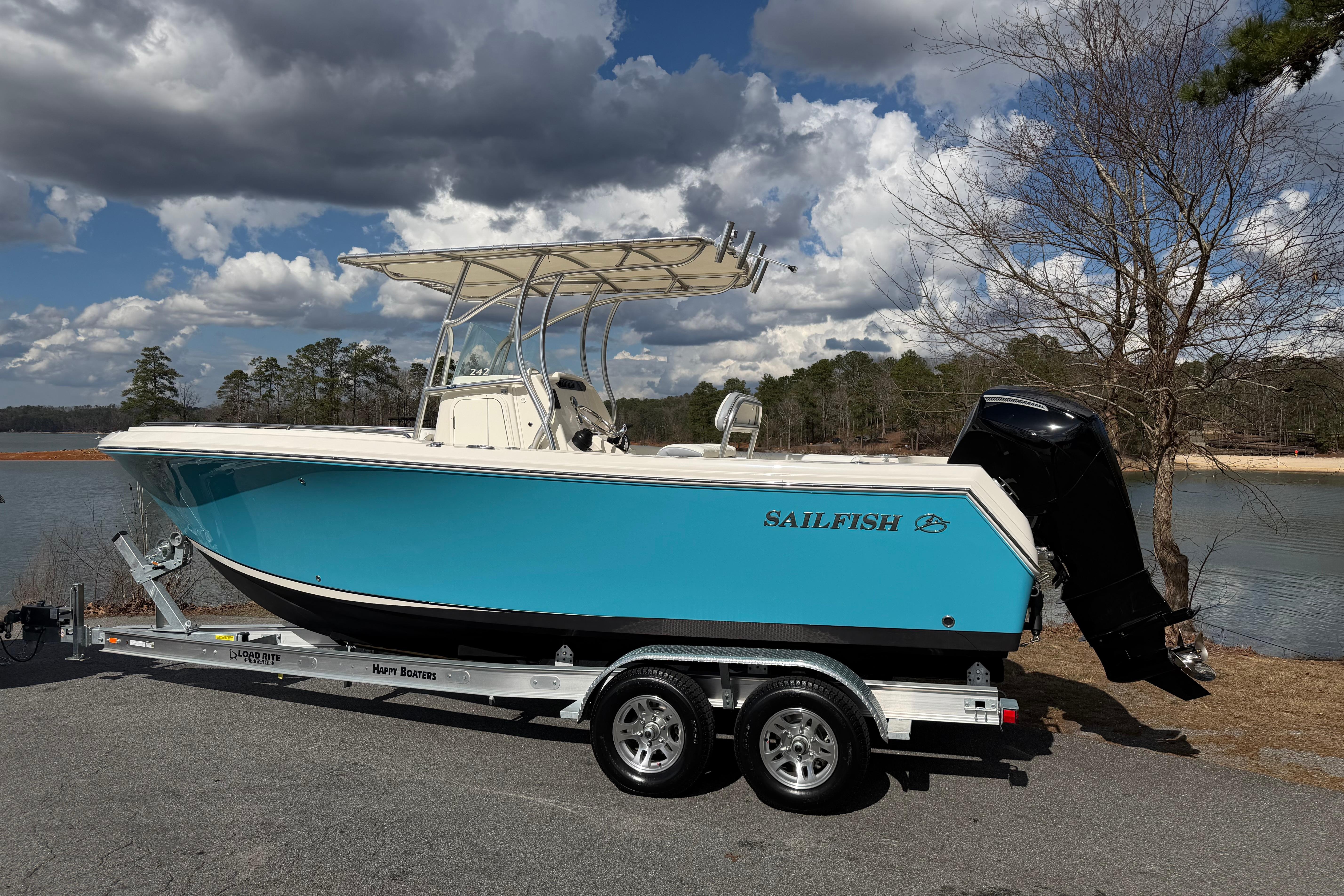 2022 Sailfish 242 CC boat on trailer by a lake under cloudy sky.
