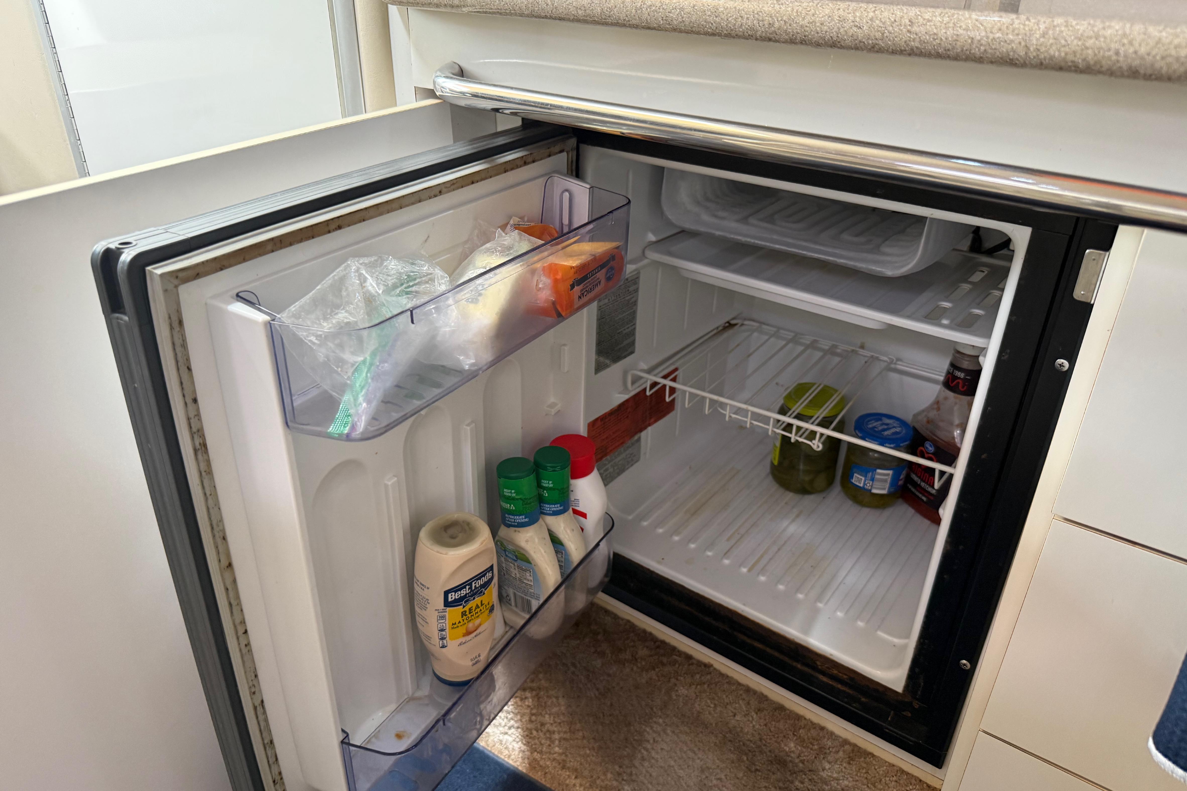 Mini fridge inside 1999 Chaparral Signature 300 boat, stocked with condiments and groceries.
