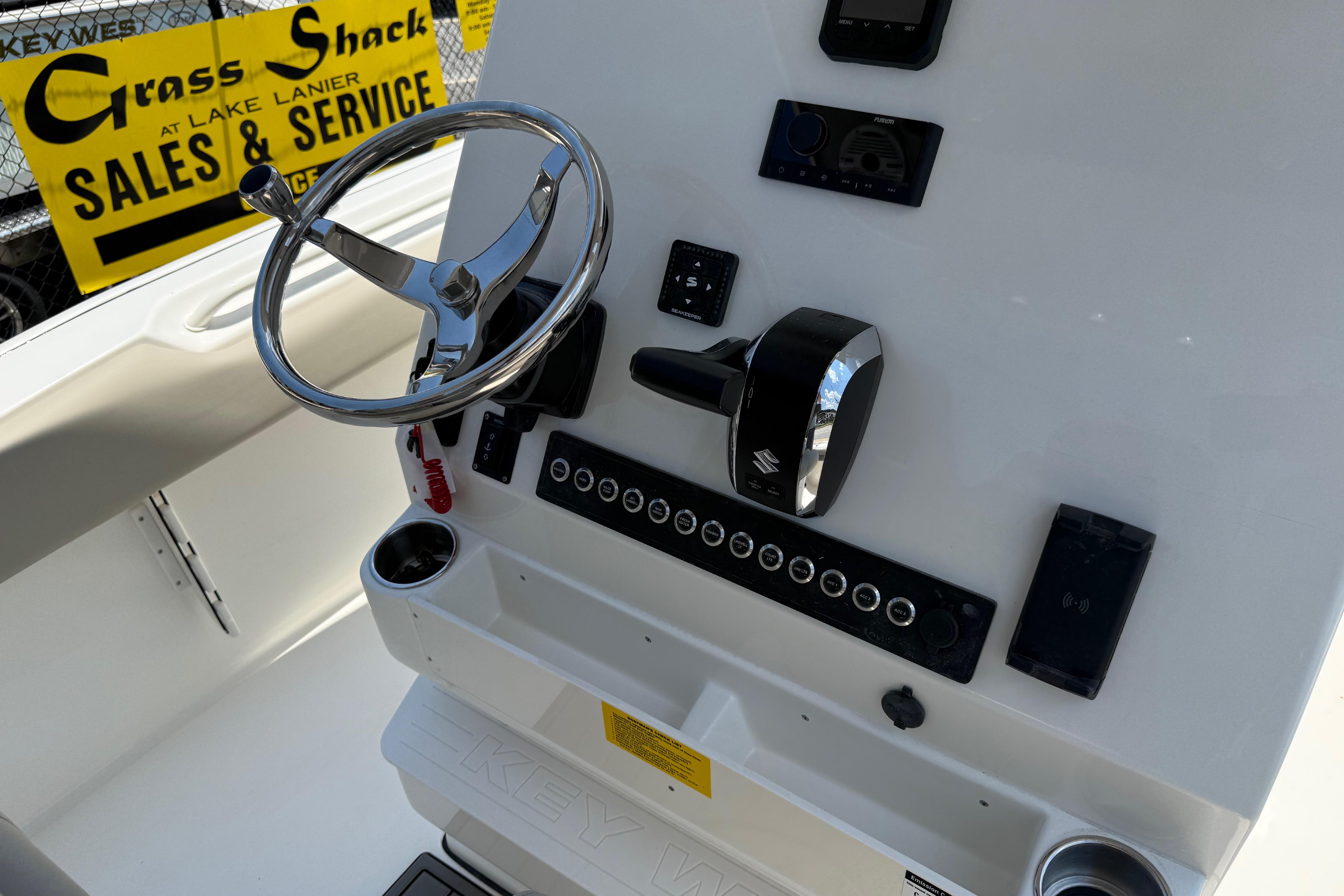 2027 Key West 249 FS boat dashboard with steering wheel and controls, Grass Shack sales sign visible.