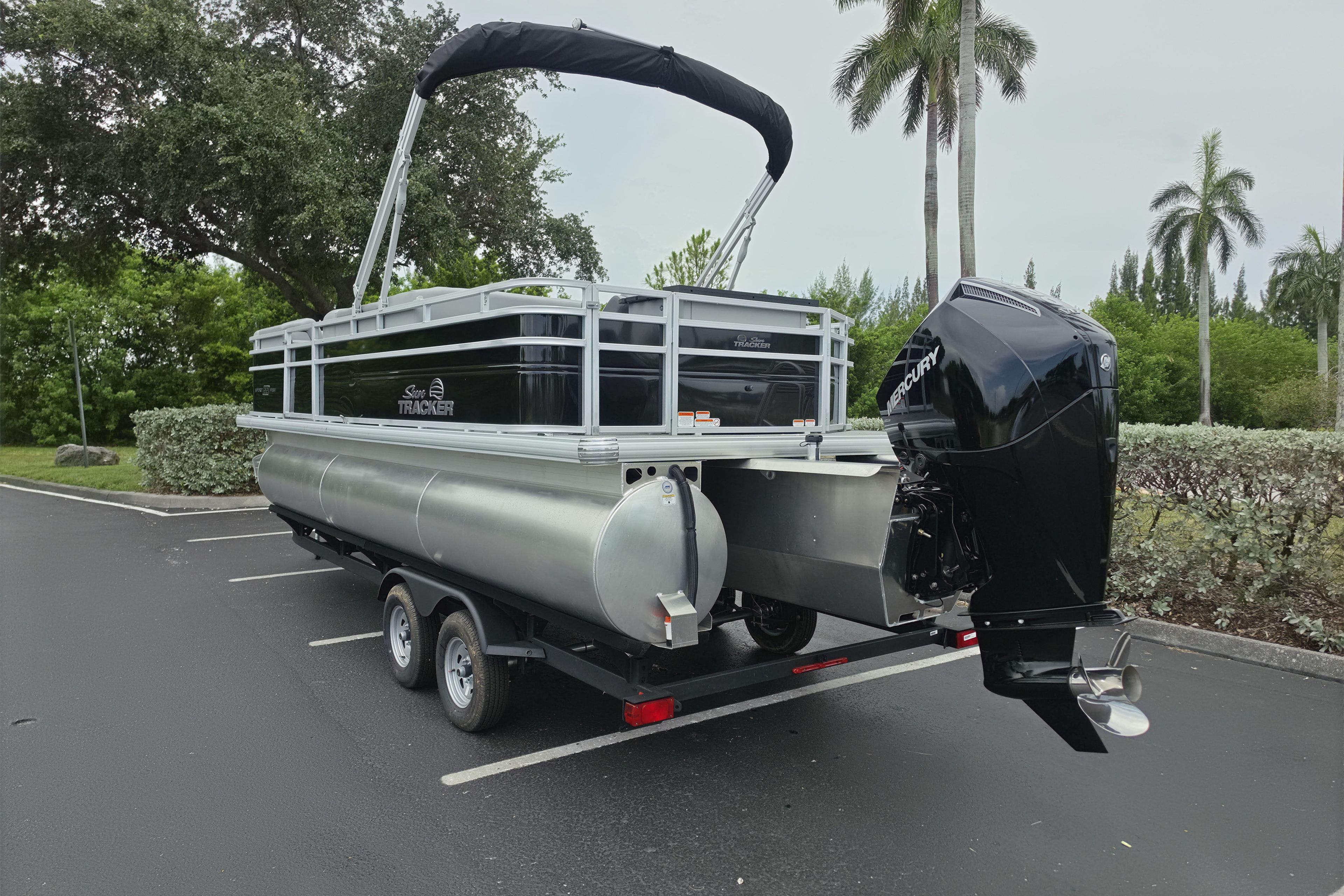 2026 Sun Tracker SportFish 22 XP3 pontoon boat with Mercury outboard motor in a parking lot.
