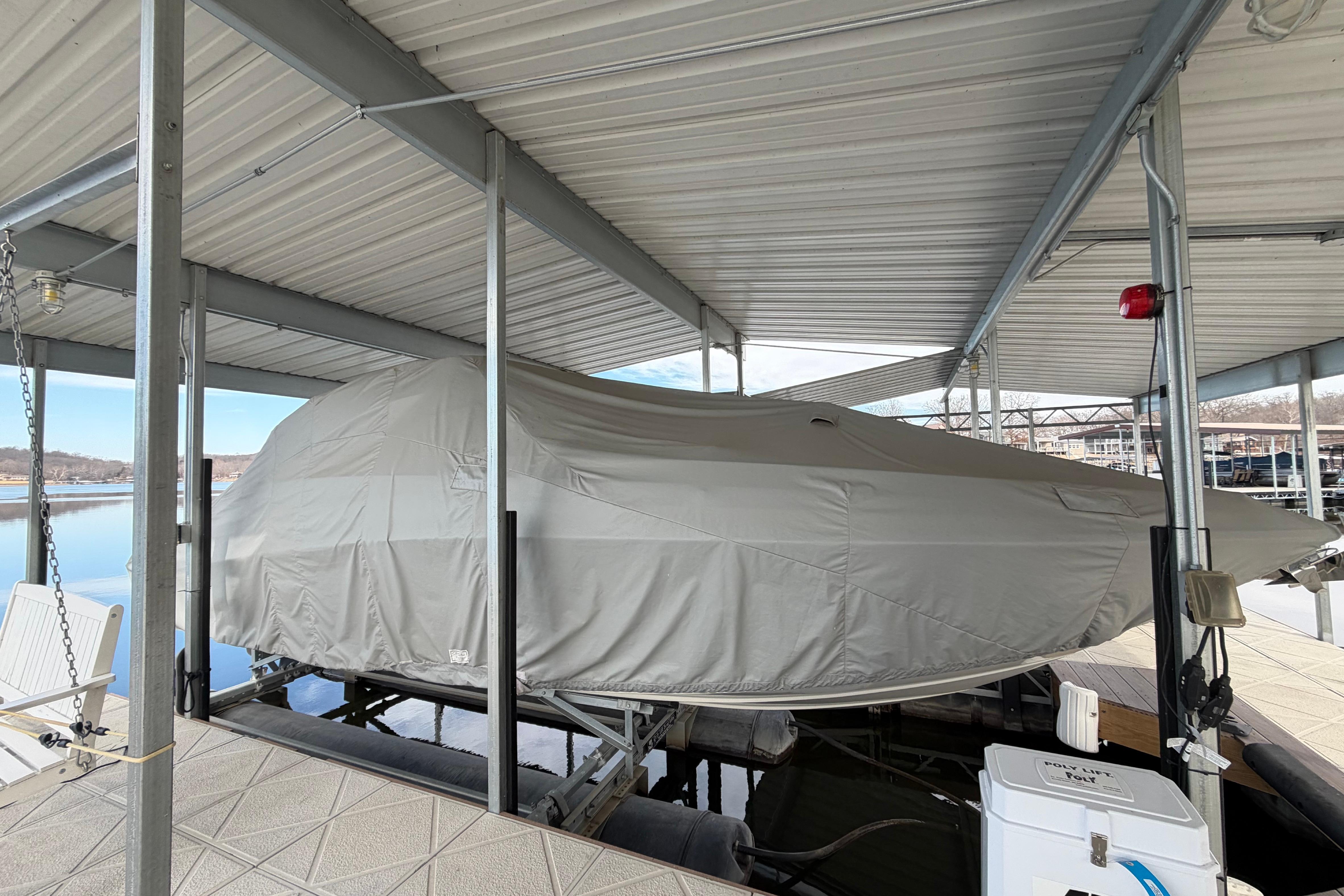 Covered 2022 Crownline 265 SS boat docked under a metal canopy.