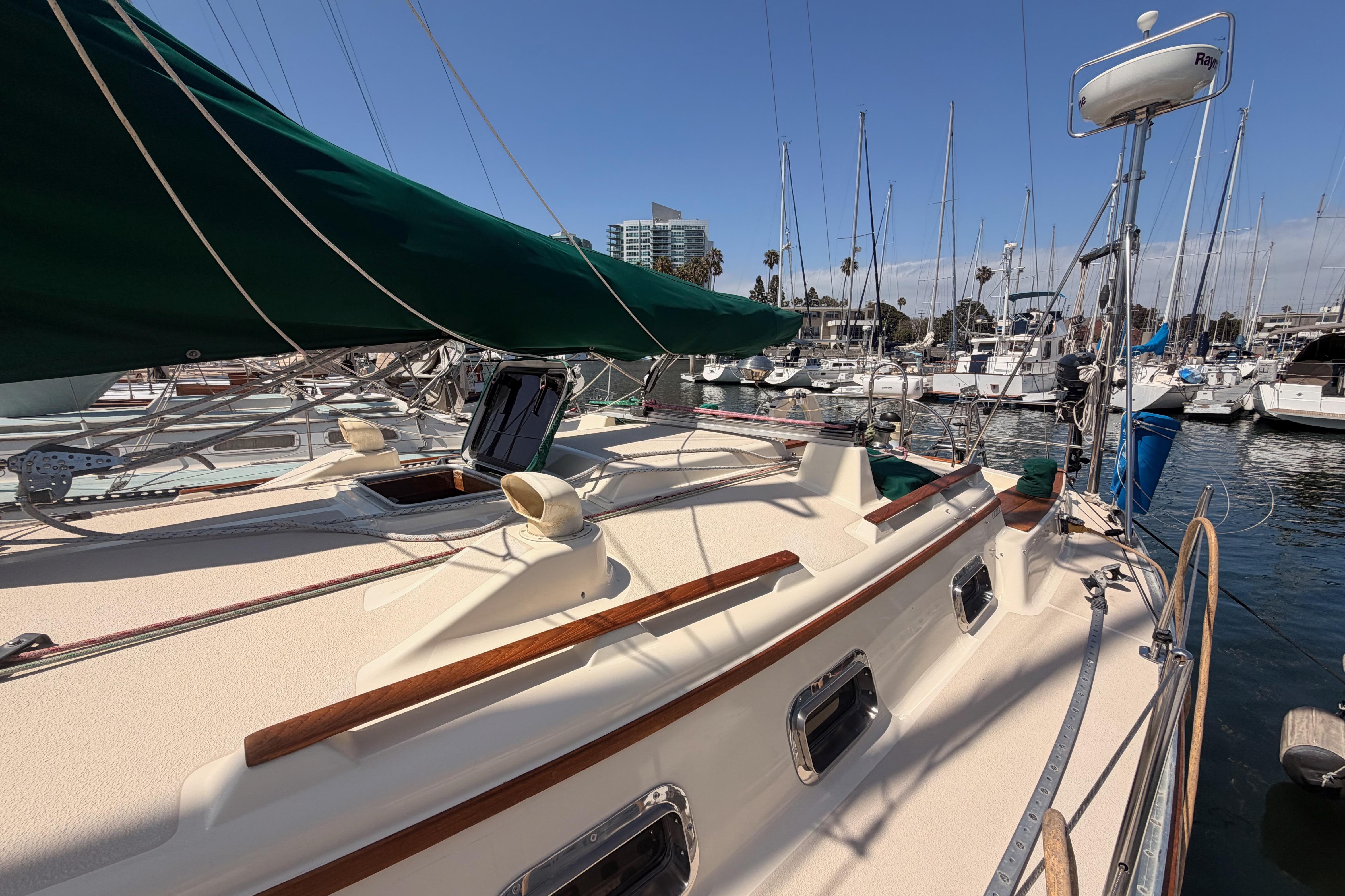 1991 Caliber 33 sailboat docked at marina with green sail cover.
