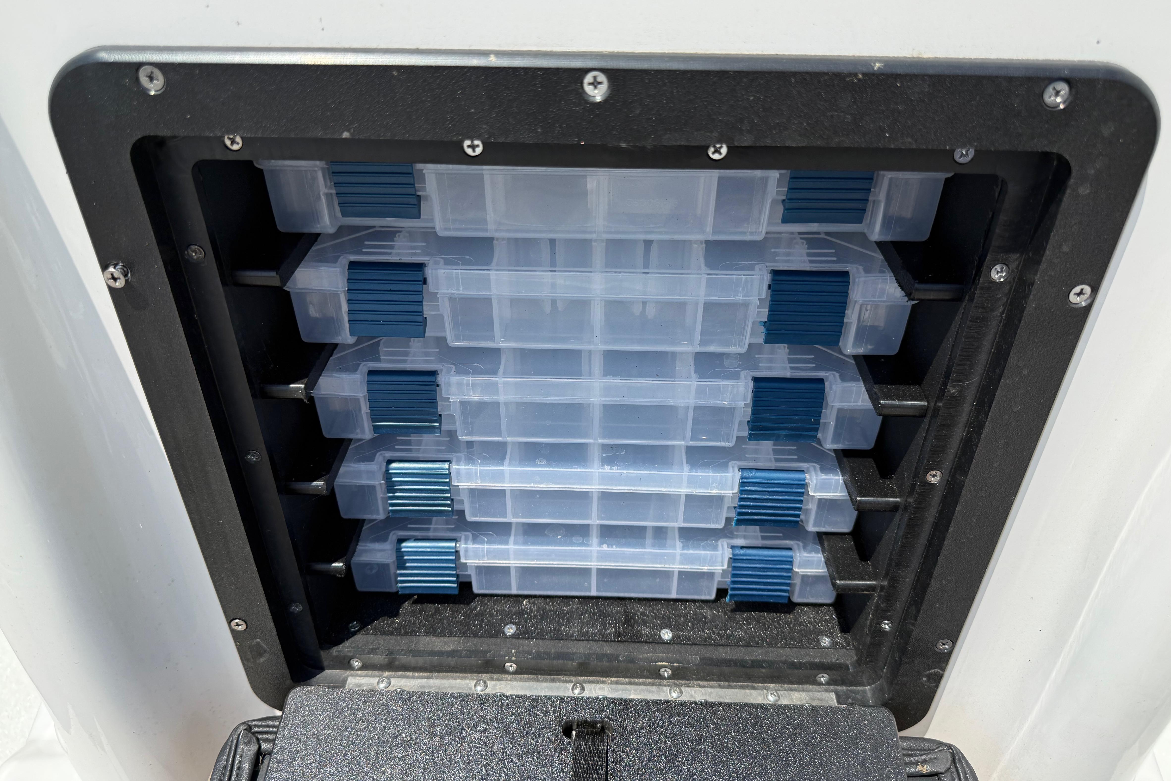 Storage compartment with clear plastic containers in a 2025 Avid 22 Recon boat.