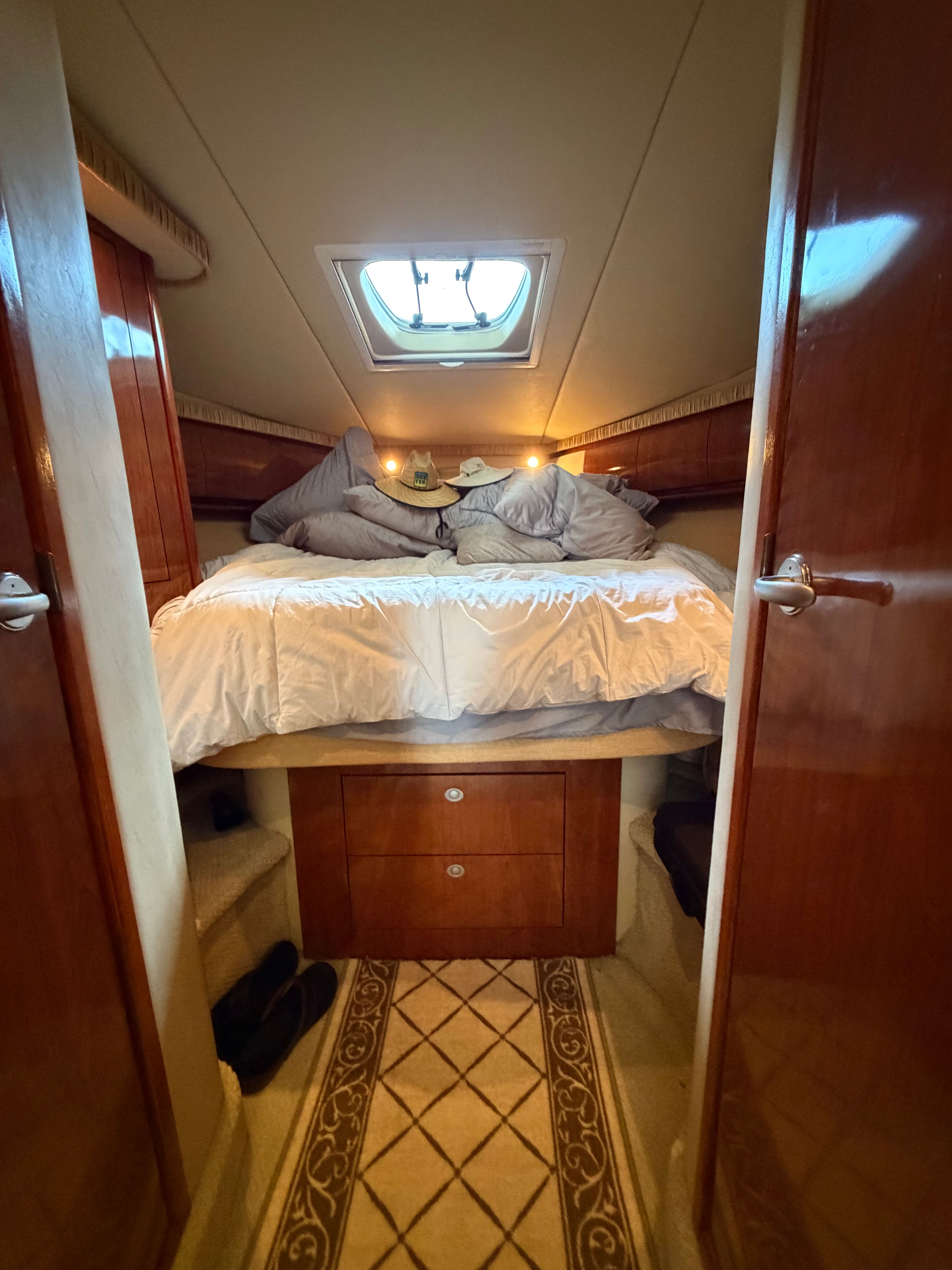 Cabin with double bed, wooden furnishings, and skylight on a 2005 Sea Ray 420DA.