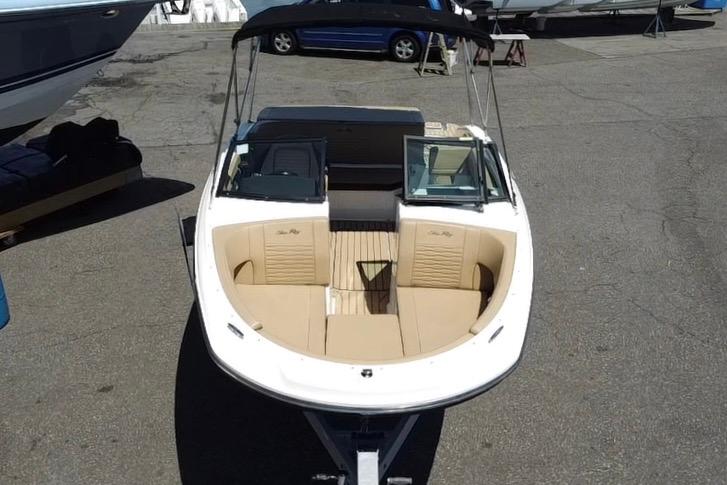 2021 Sea Ray SPX 190 boat with beige seating and black canopy, parked on pavement.